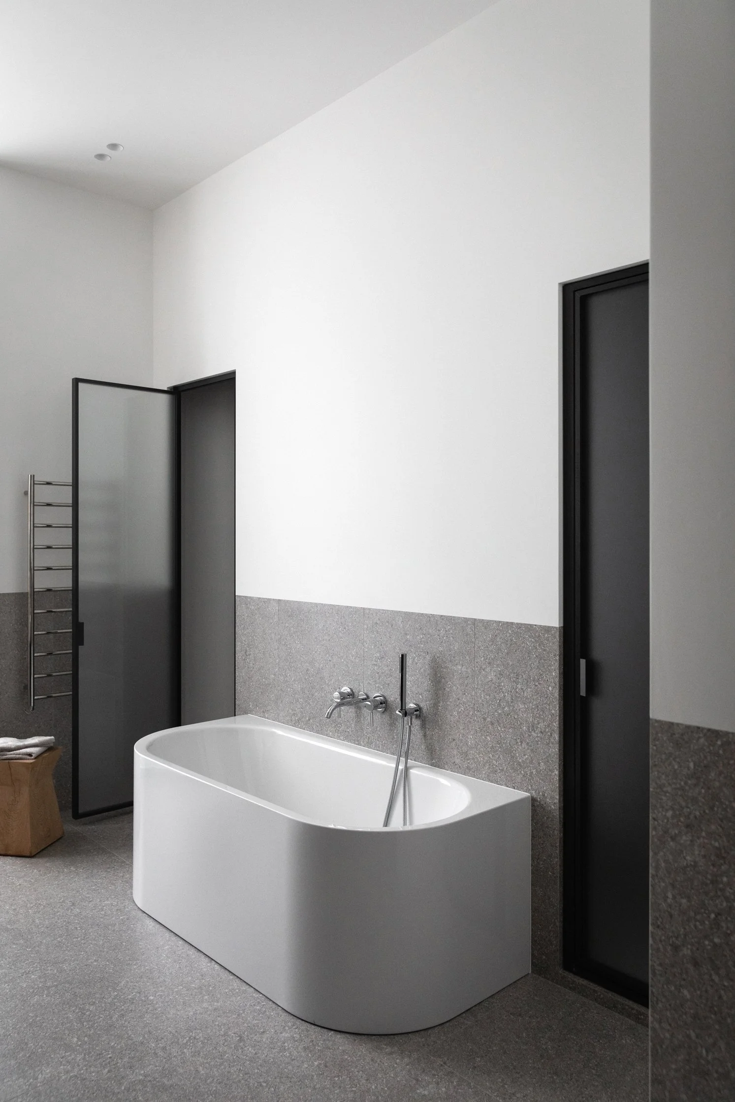 Salle de bain contemporaine avec baignoire îlot et parement en gré cérame effet pierre dans un appartement rénové
