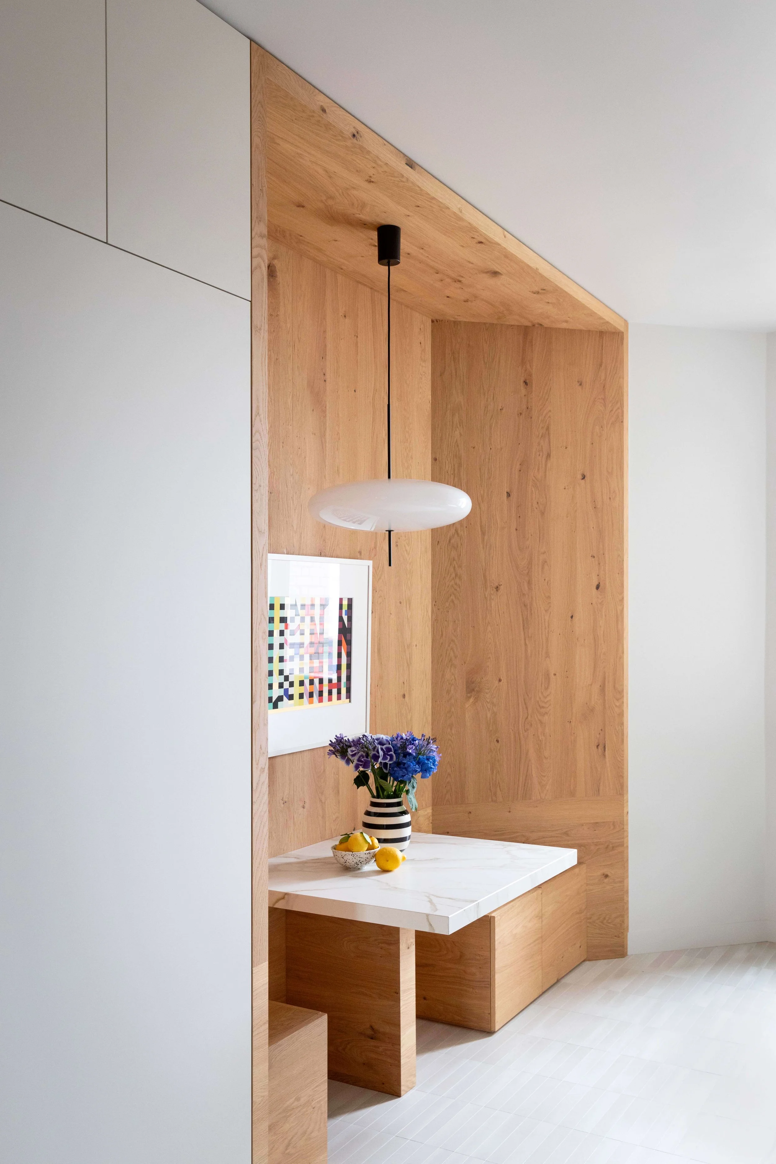 Coin repas en bois intégré à la cuisine sur mesure d’un appartement rénové à Paris 16