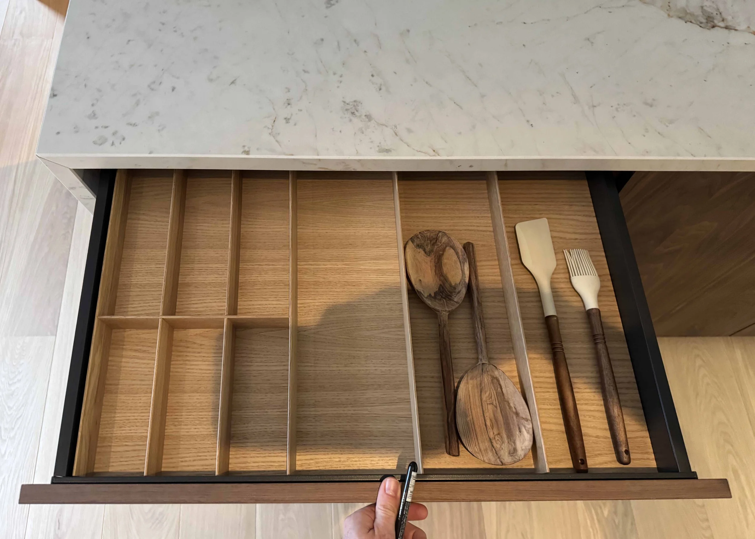 Pose des range couverts en bois dans une cuisine réalisée sur mesure dans un appartement dans le Marais à Paris