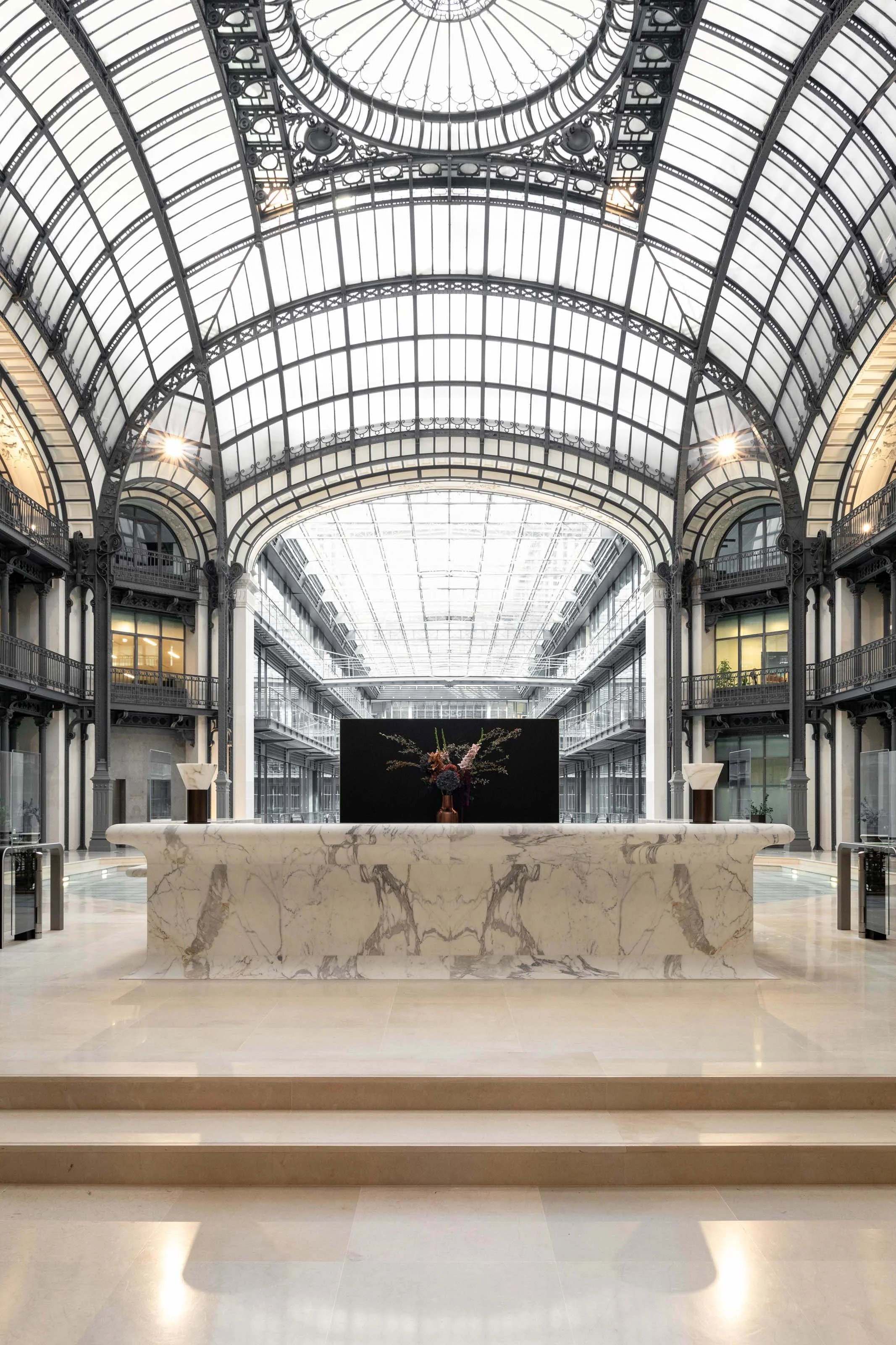 Hall d’accueil d’un immeuble de bureaux à Paris 2 avec banque en marbre et coupole métallique