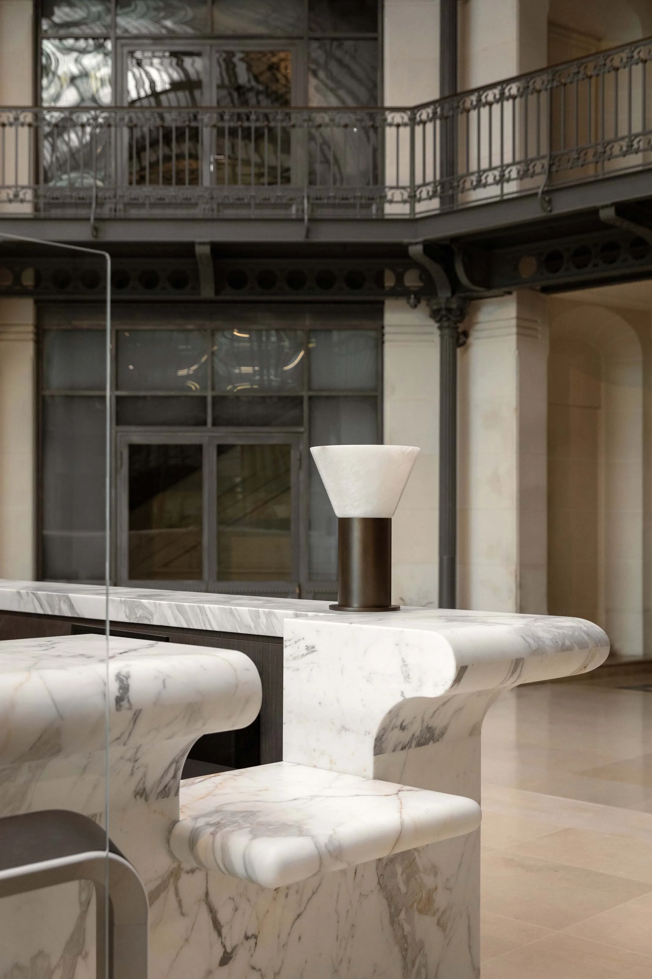 Détail du comptoir en marbre et d’un luminaire en laiton et albâtre dans un hall de bureaux