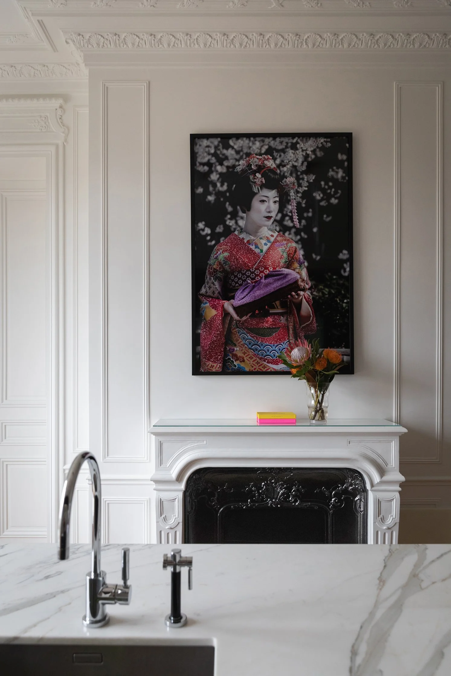 Cuisine en pierre claire dans un appartement haussmannien rénové à Paris 16, avec cheminée et moulures restaurées