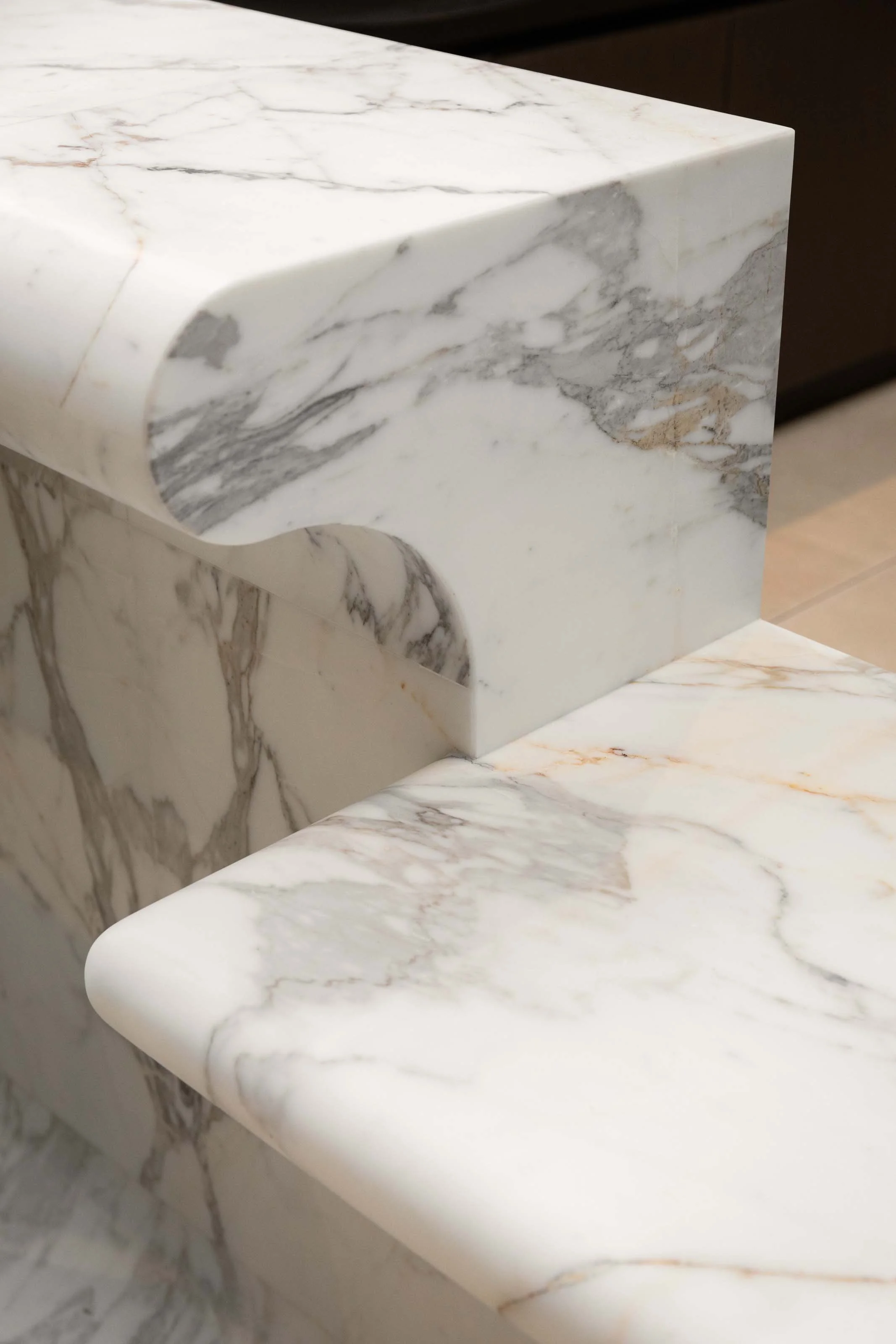 Détail du marbre Calacatta Oro et des formes arrondies de la banque d’accueil sur mesure