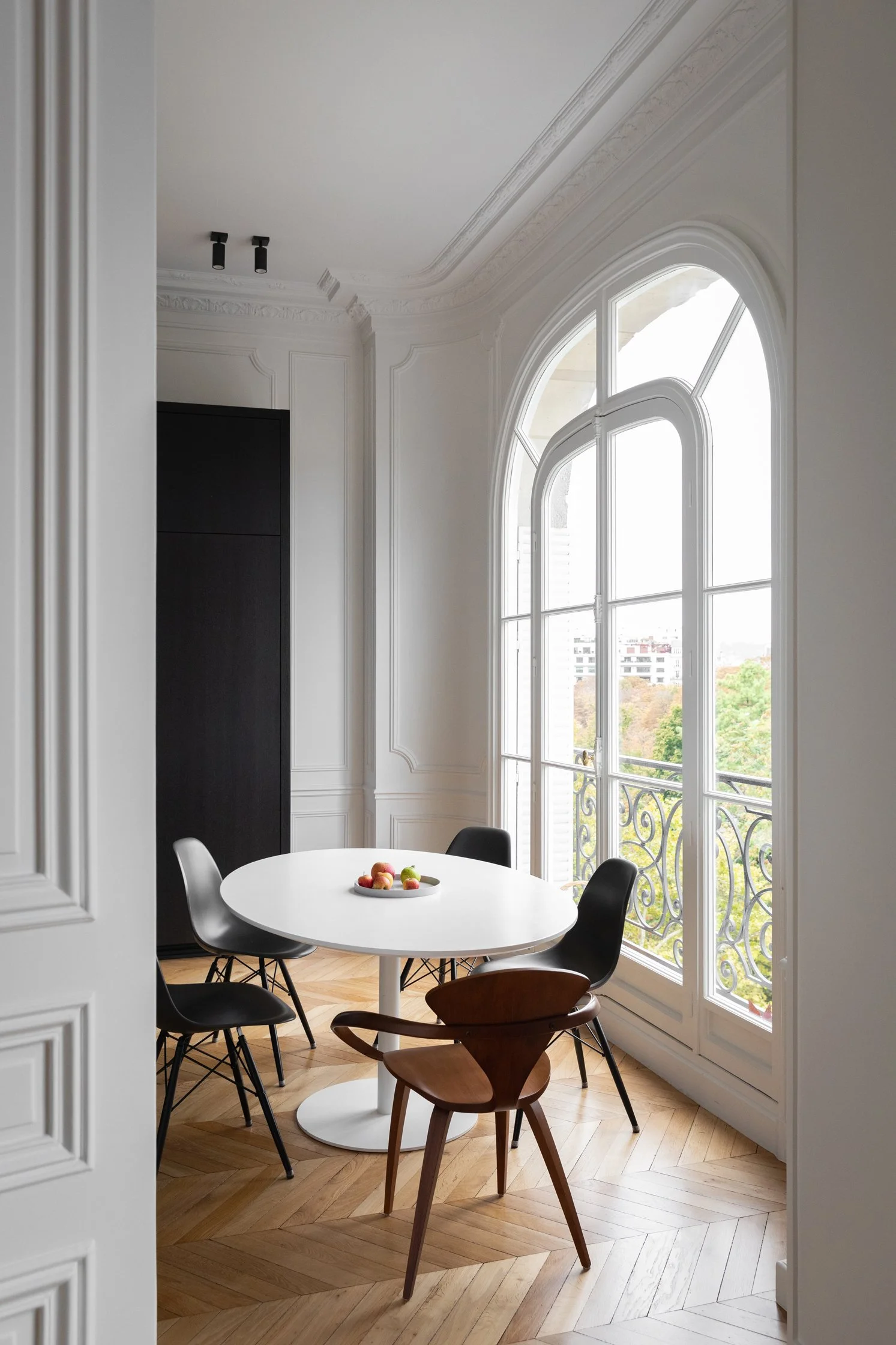 Salle à manger lumineuse devant une fenêtre haussmannienne dans un appartement rénové à Paris 16