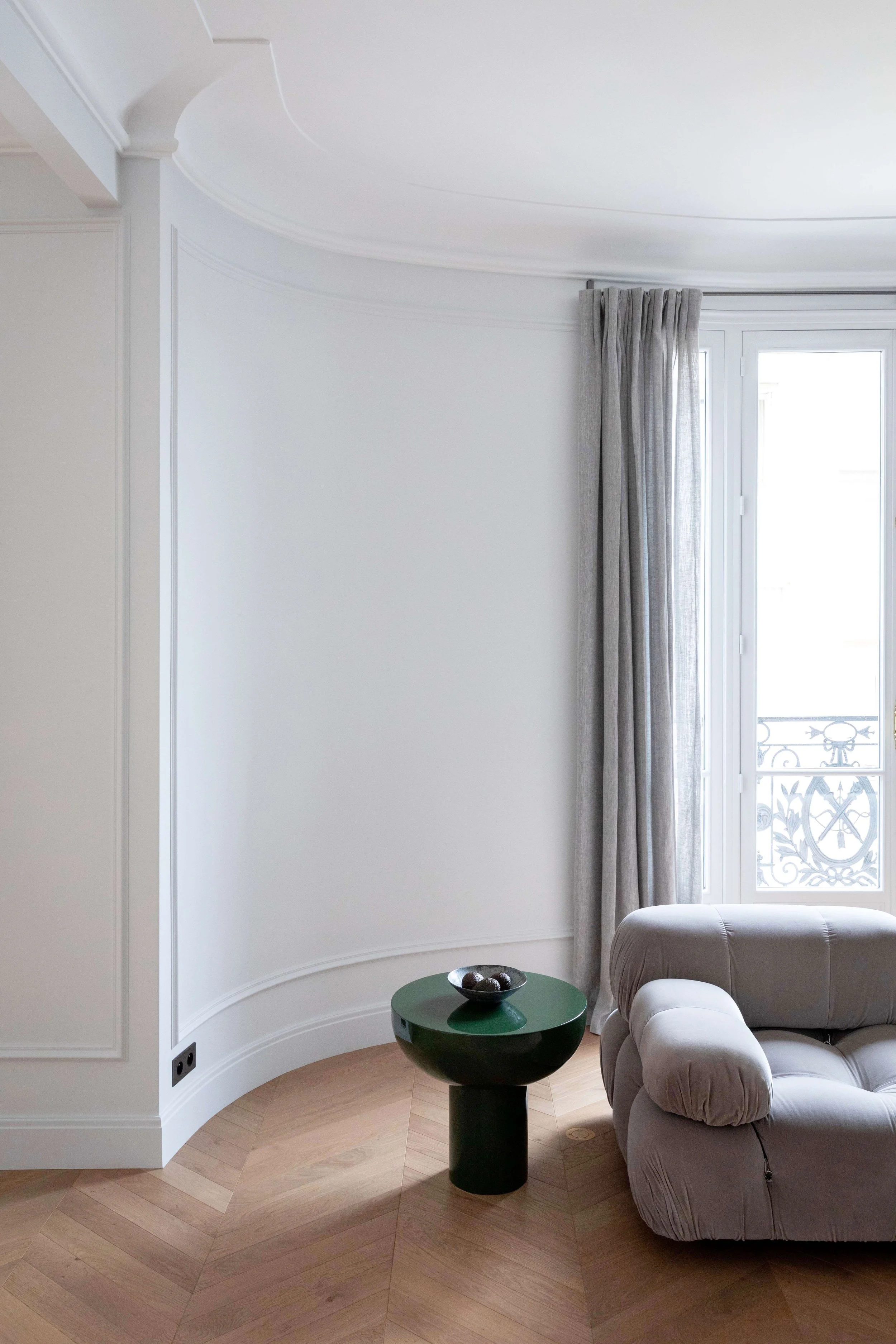Détail du salon d’un appartement haussmannien à Paris 16 avec moulures, fenêtre et mobilier contemporain