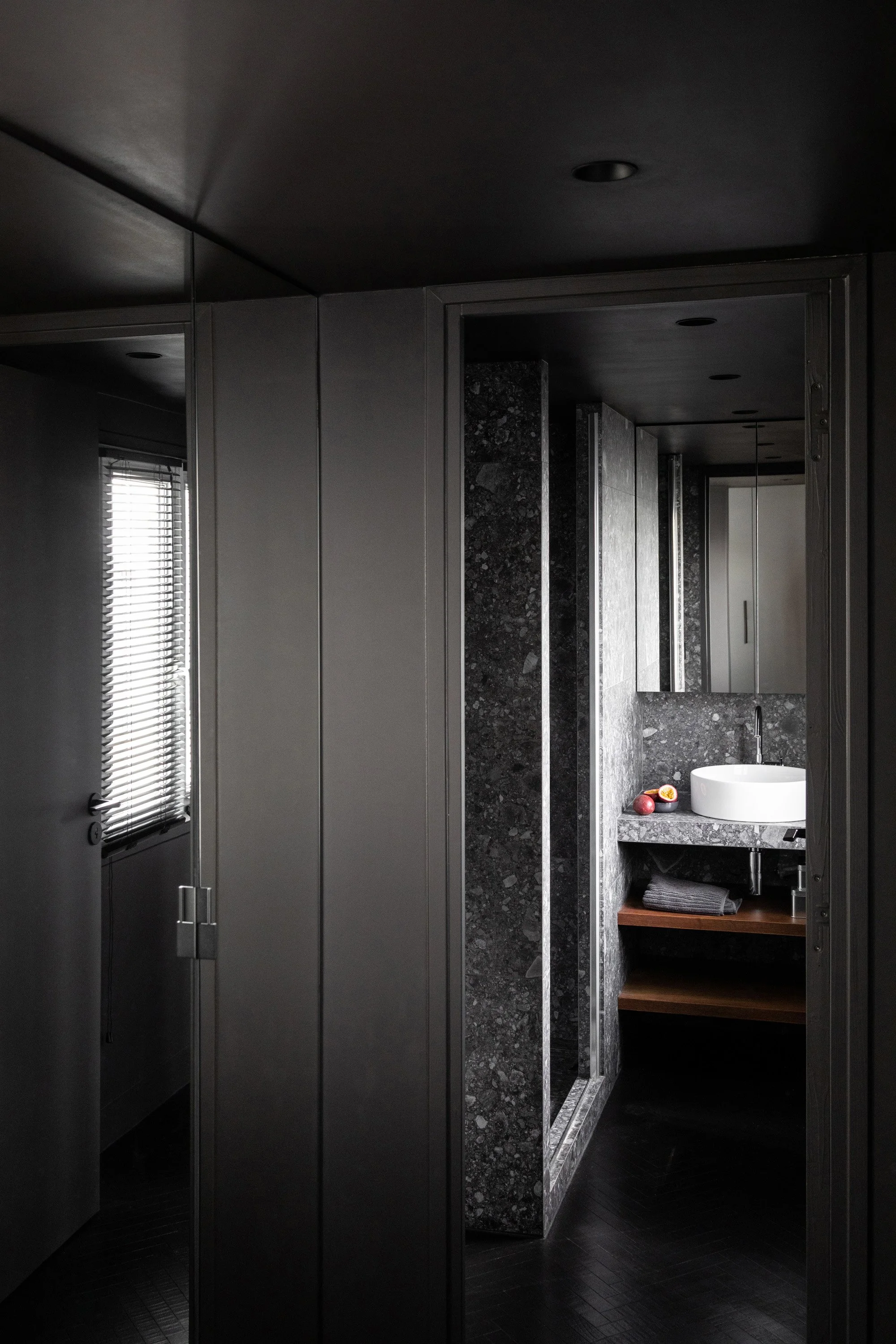 Salle de bain sombre en pierre et bois dans un appartement rénové à Paris 9