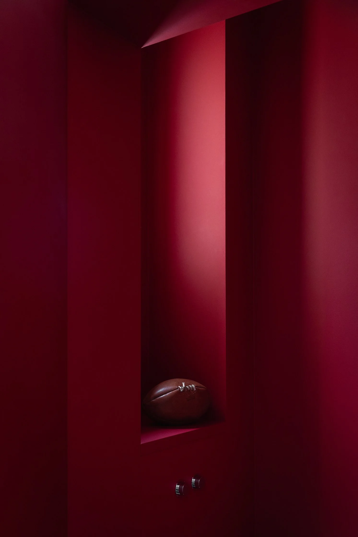 Niche rouge intégrée dans une salle de bain avec rangement sur mesure et détail de robinetterie et du WC
