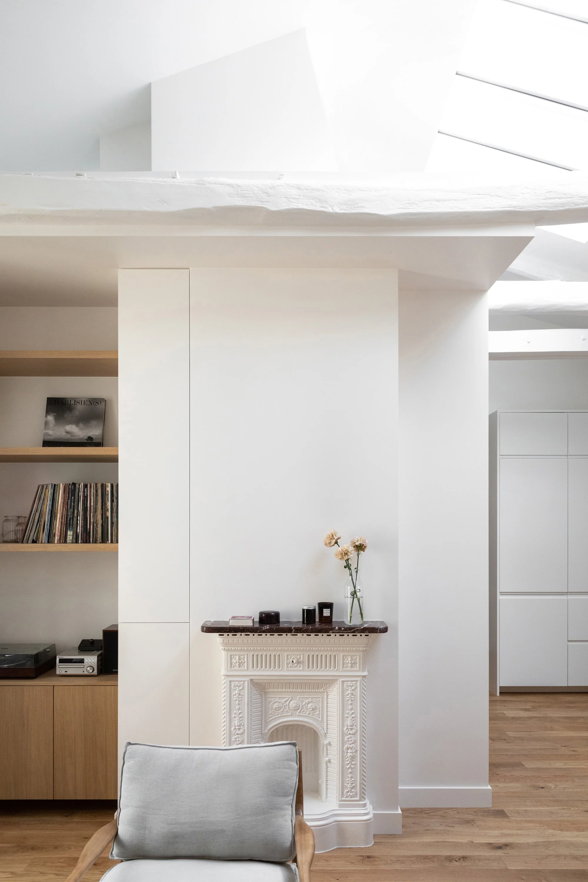Cheminée ancienne sous verrière de toit dans le séjour d’un appartement rénové à Montparnasse