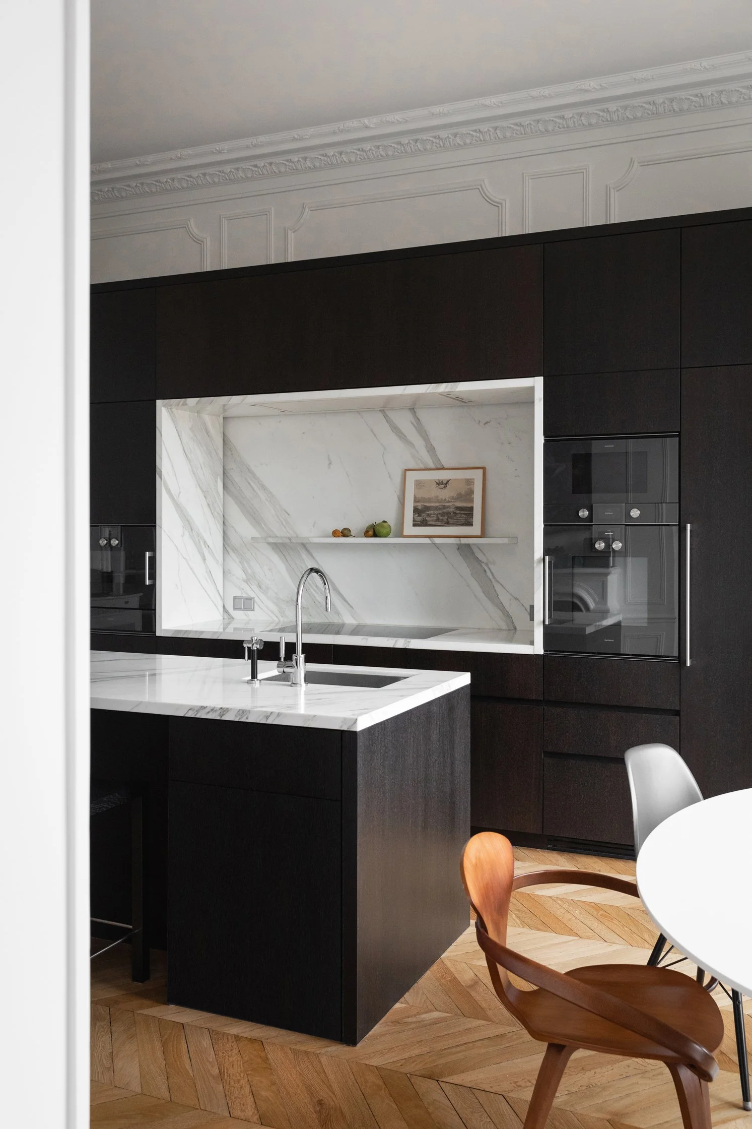 Cuisine sur mesure avec un îlot en bois sombre et pierre naturelle dans un appartement haussmannien rénové