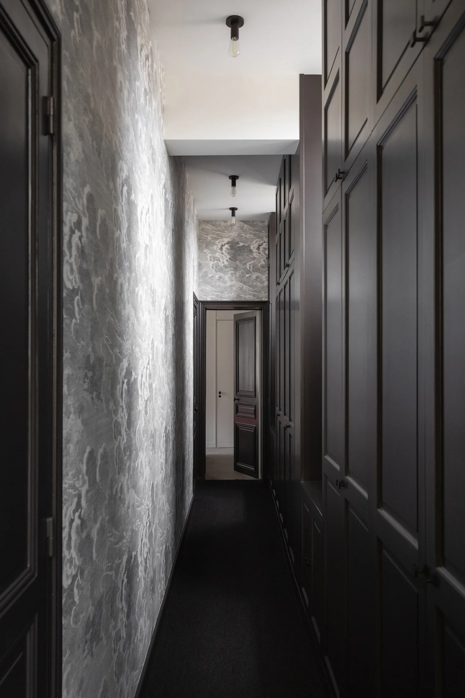 Couloir avec dressing sur mesure en bois sombre et papier peint texturé dans un appartement parisien