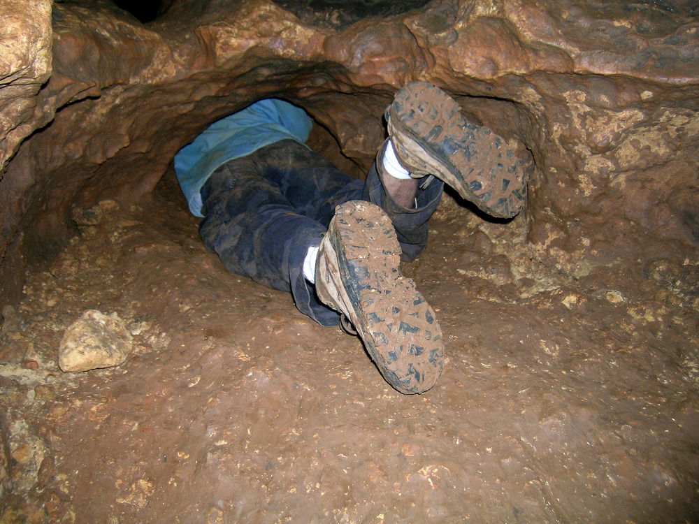 Someone crawling into a small cave.