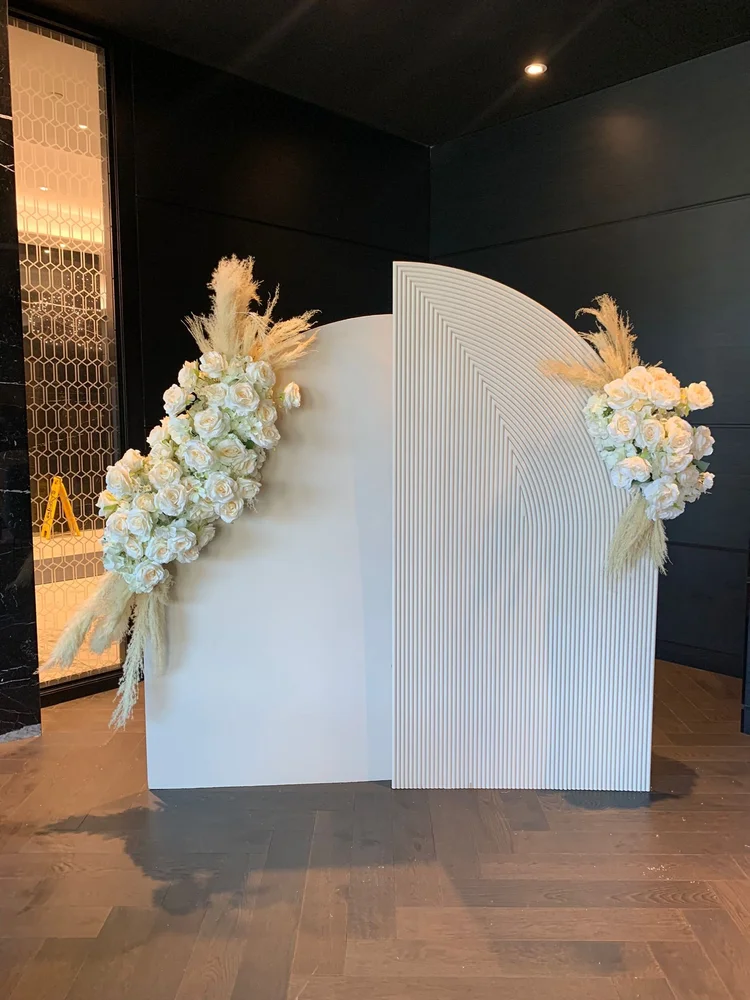 White arched event backdrop with floral decoration