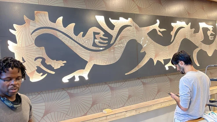 Decorative dragon panel being fitted above restaurant seating