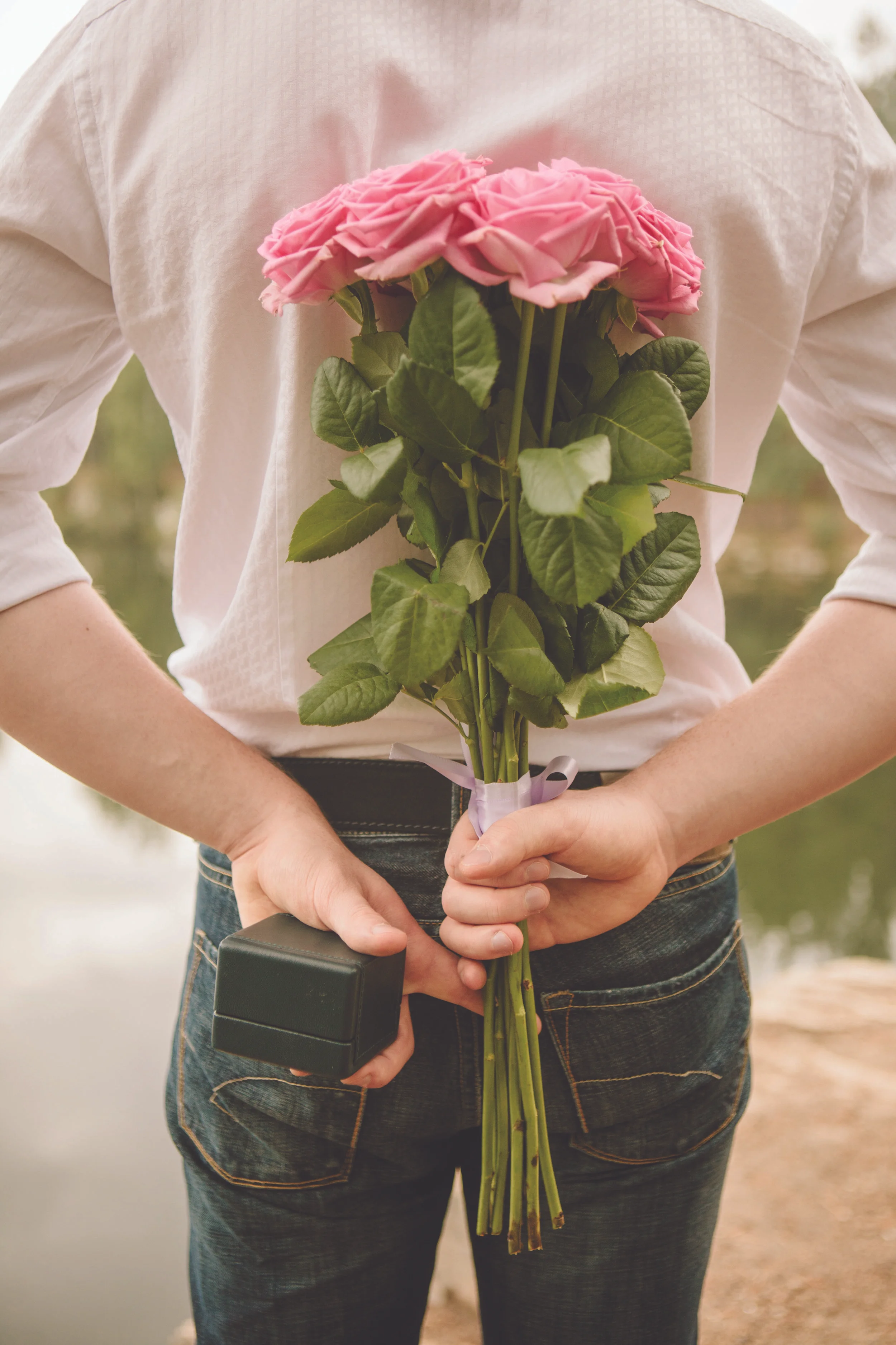 Valentines day. Man hiding behind a bouquet of flowers. Proposal