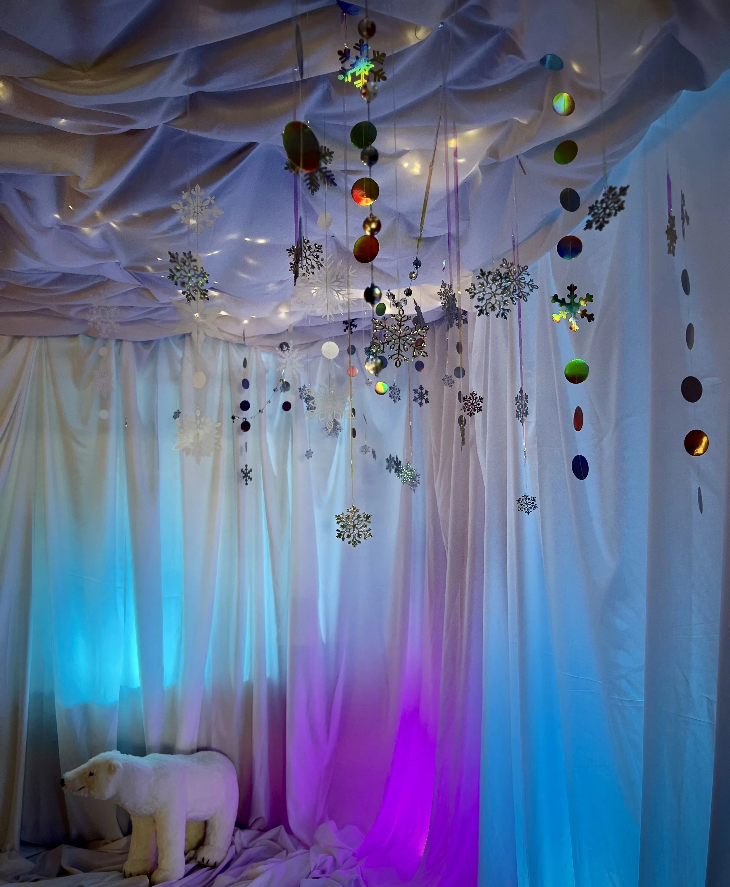 blue and fuchsia lighted fabric wall with fairy lights, stars and a stuffed white polar bear on floor