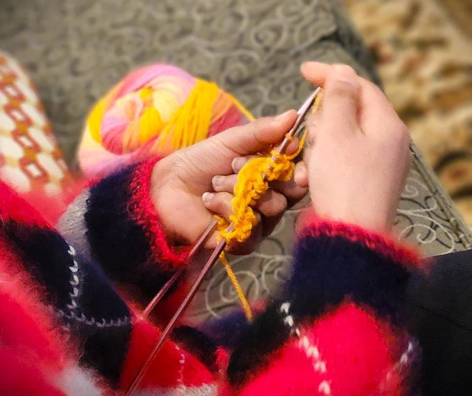 girl in argyle sweater, knitting a yellow scarf