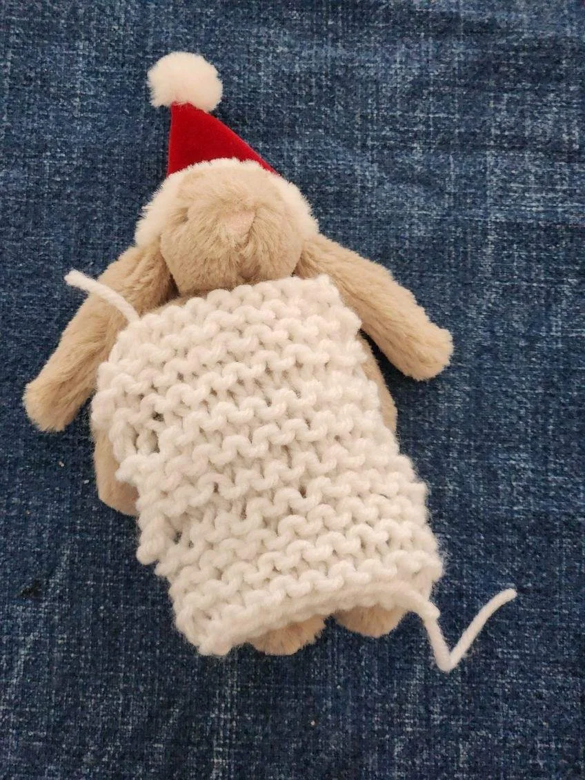stuffed bunny with santa hat and crocheted ivory blanket