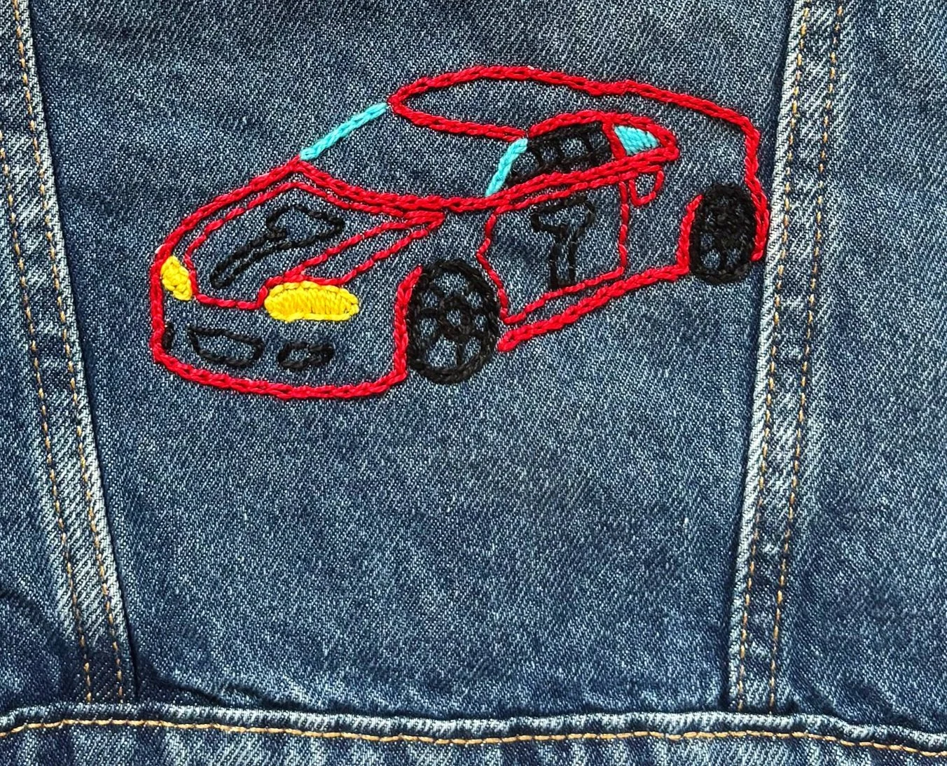 embroidered red sportscar on a jean jacket with yellow lights