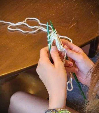 hands knitting with green needles and mint yarn