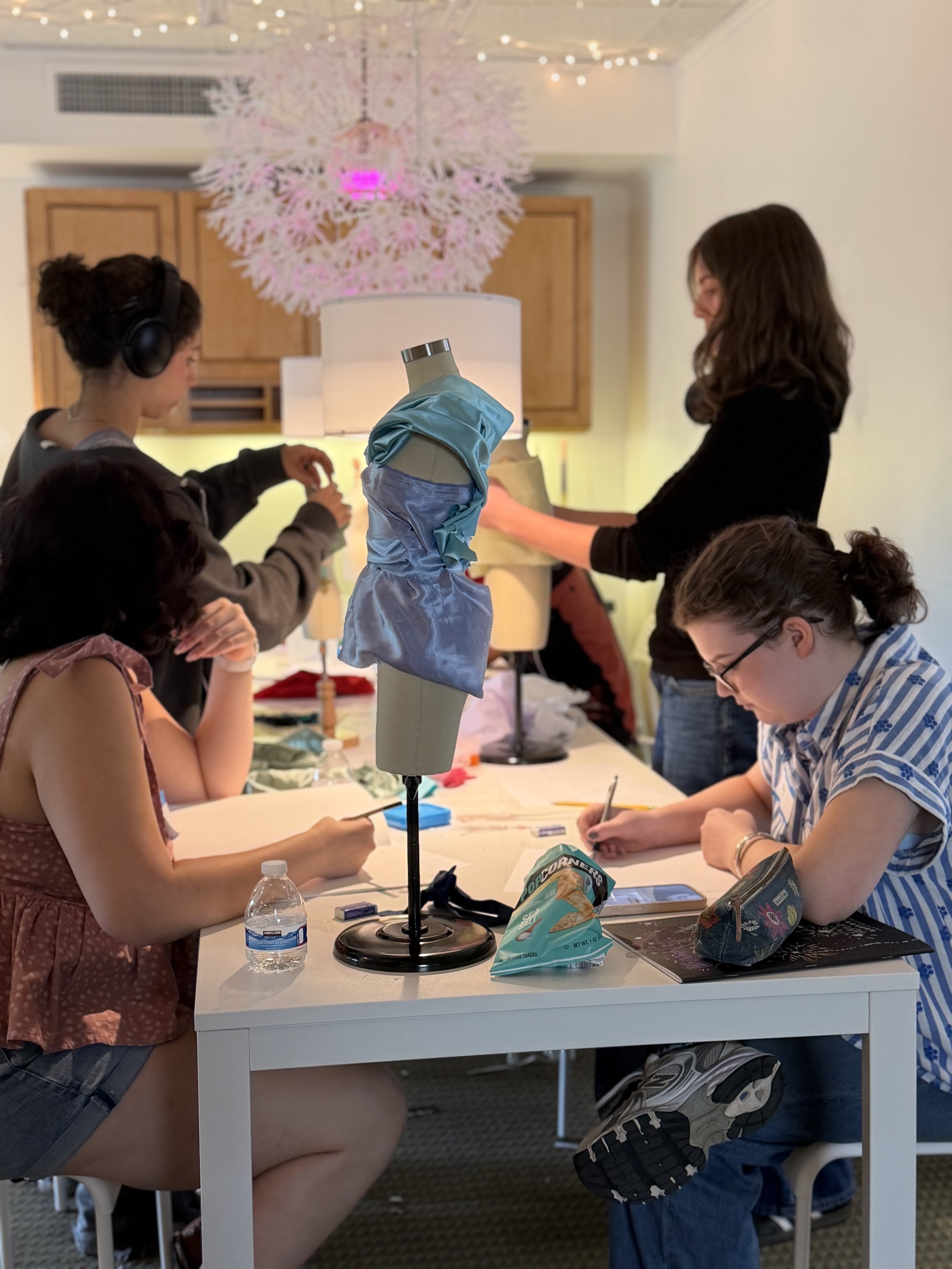 Group of teen girls draping and drawing in class, on white table