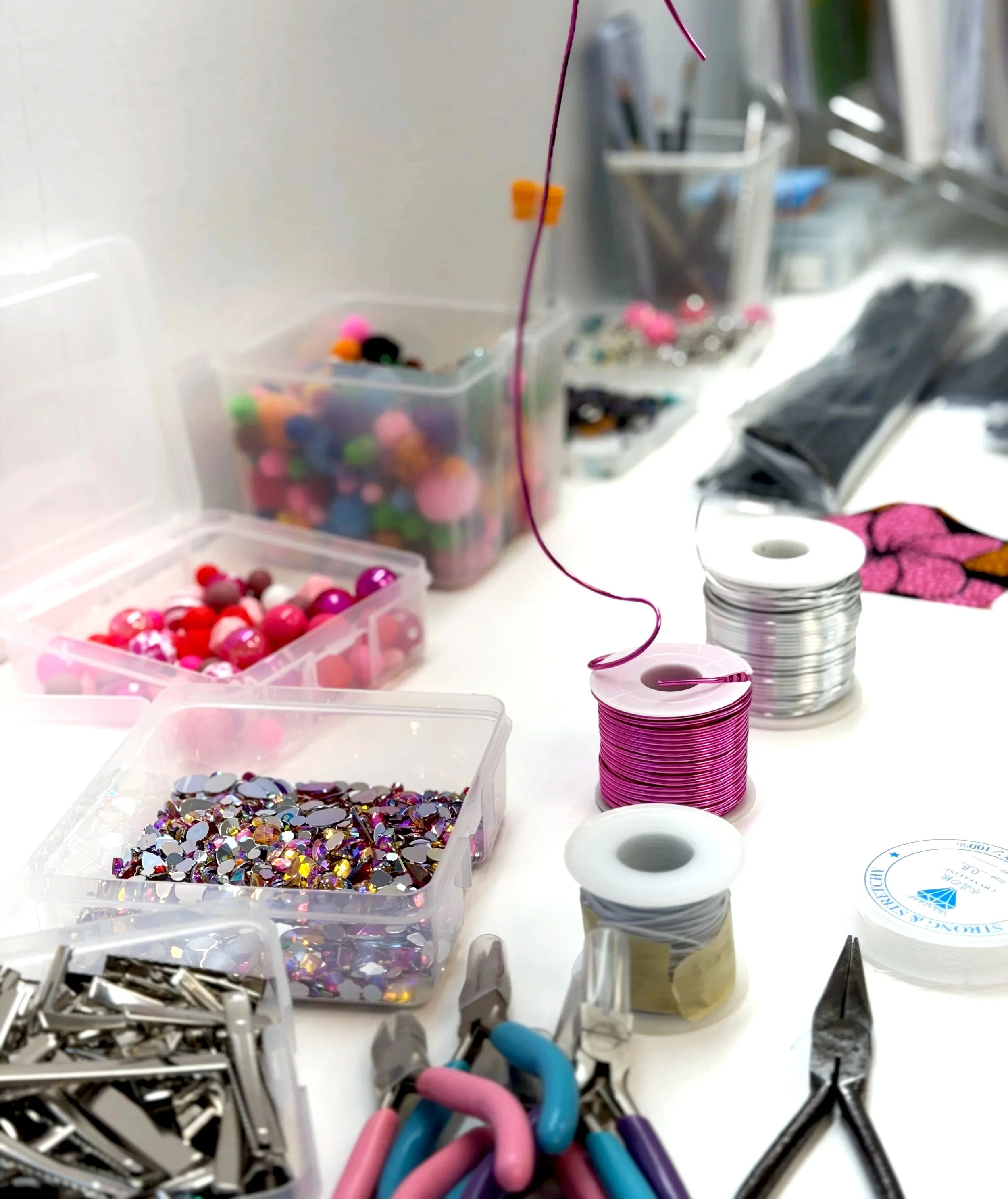 craft supplies for making jewelry and beads with fuchsia and silver metal rolls and colorful beads