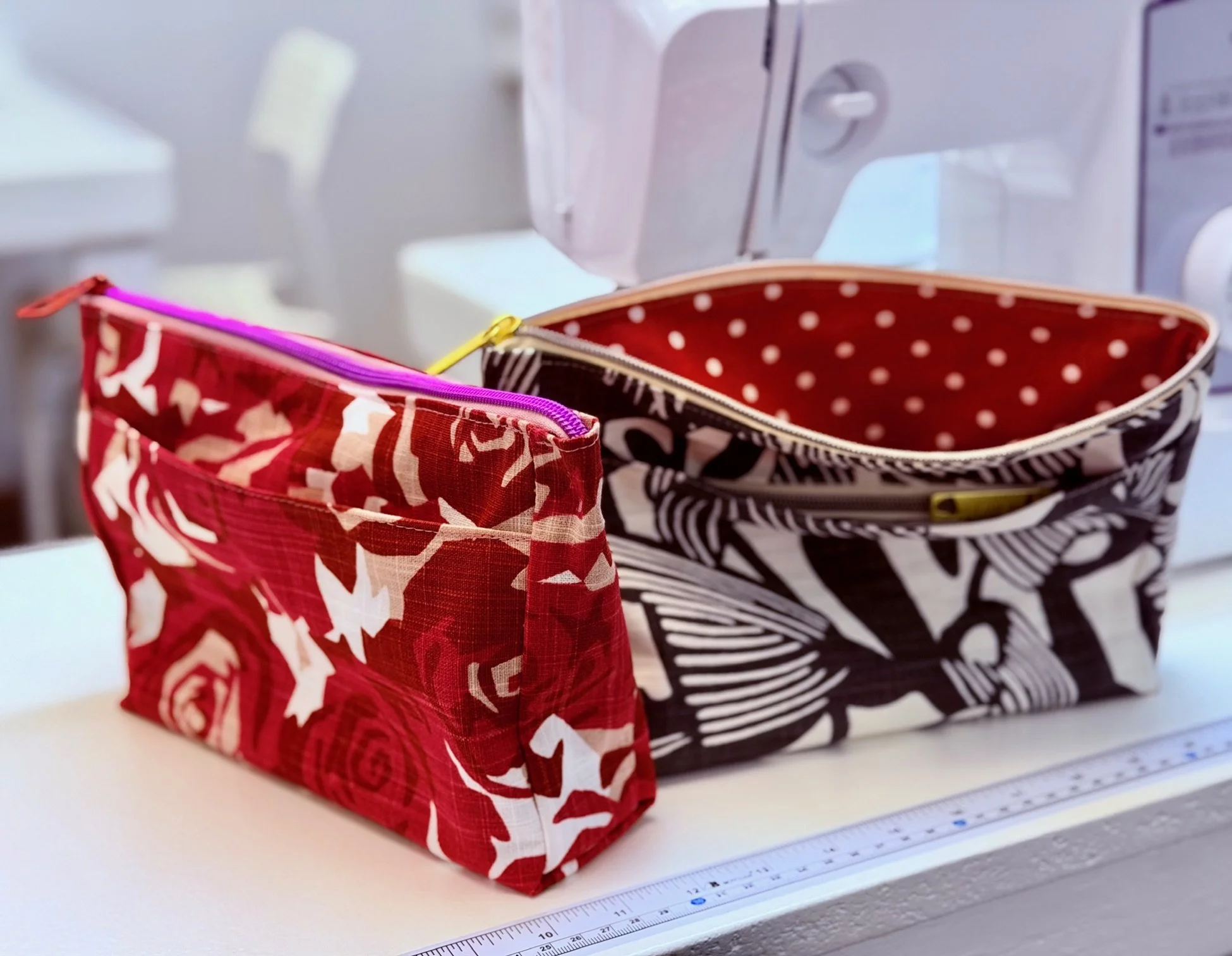 two zipper bags in bright colors and linings, red and white with fuchsia zipper, black and white with red polka dot lining