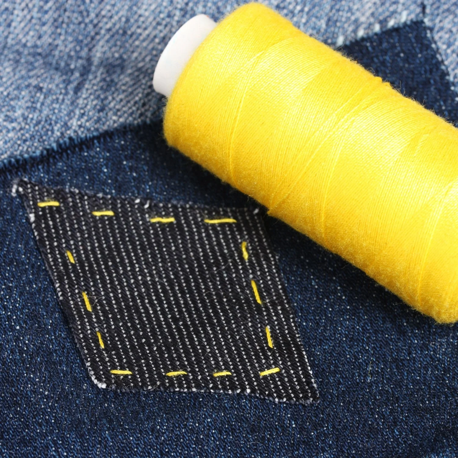 Dark blue denim patch sewn on with yellow thread