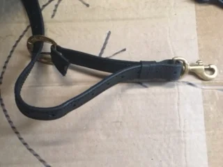 The bottom of the breastplate has a snap that is not stitched, it is held in place by a sliding leather keeper - so it can be replaced without undoing and replacing stitching.