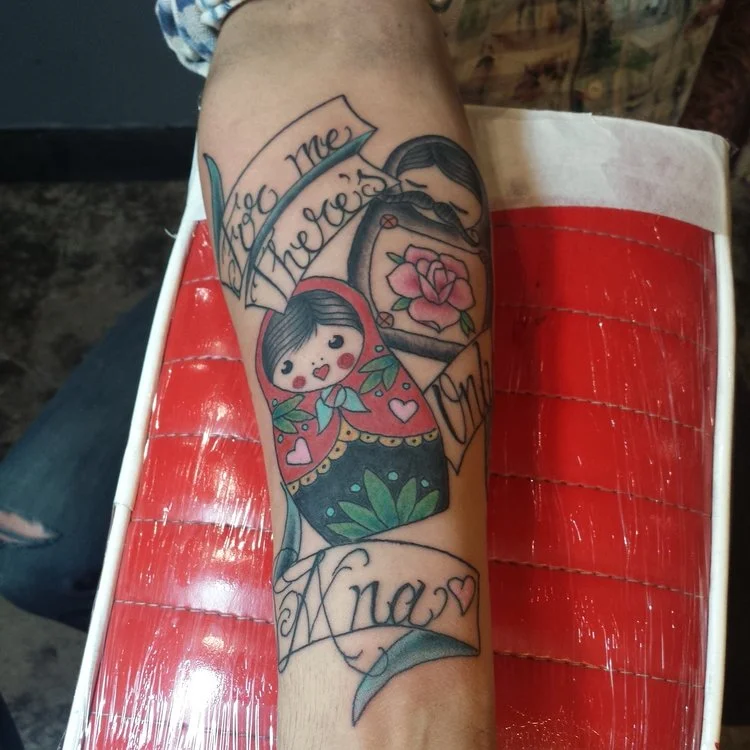 Russian nesting dolls with banners and letting. Forearm half sleeve color tattoo.