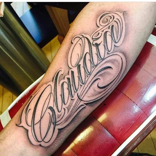 Black and gray Claudia script lettering on the forearm tattoo. 