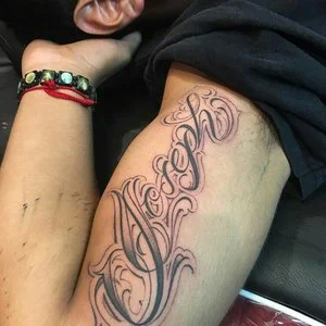 Joseph in script lettering black and gray tattoo upperarm 