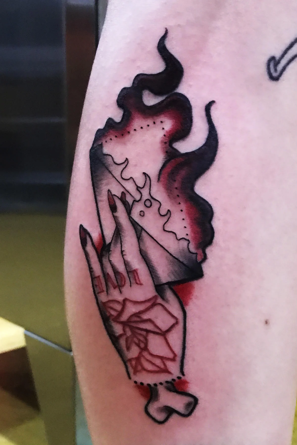 Severed female hand with a rose and lettering holding a flaming envelope. Black, gray and red coloring. Calf, half leg sleeve tattoo