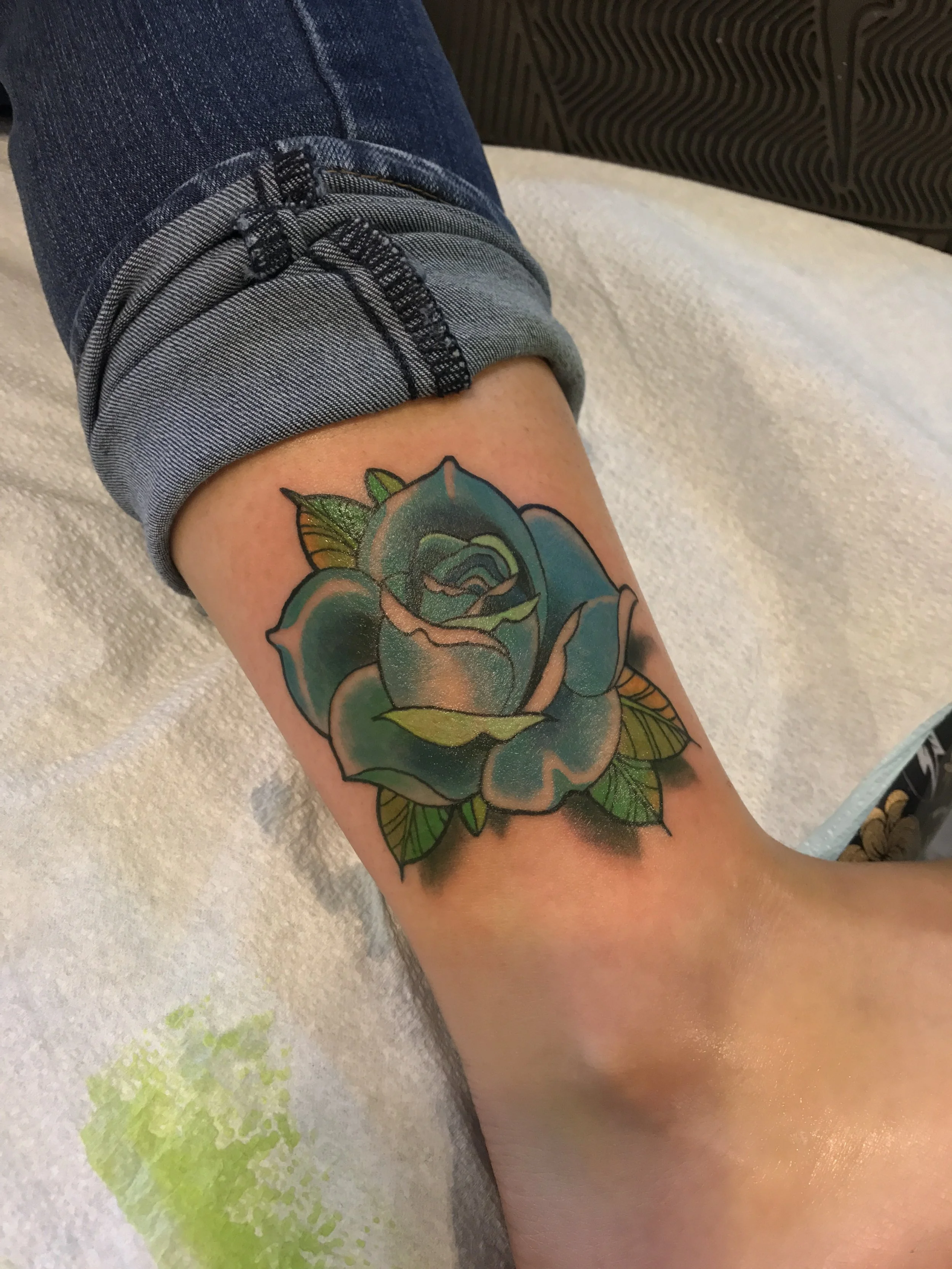 Blue rose above the anklet traditional color tattoo. 