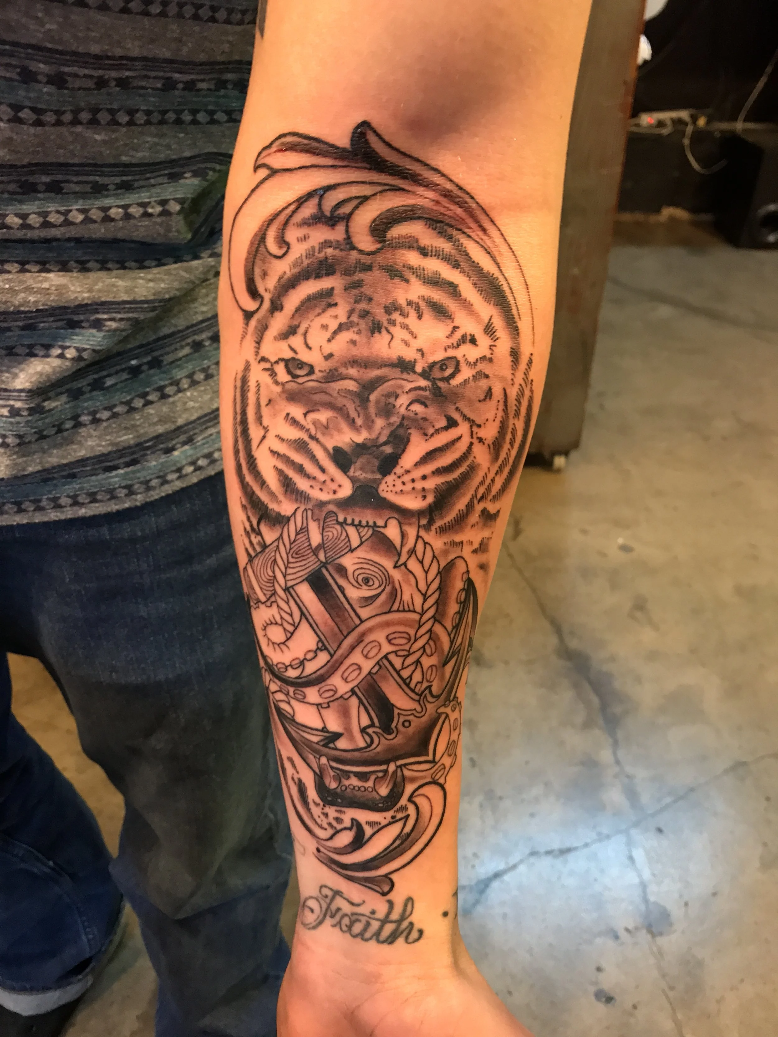 Fine detail black and gray tiger with nautical anchor and octopus in its mouth. 
