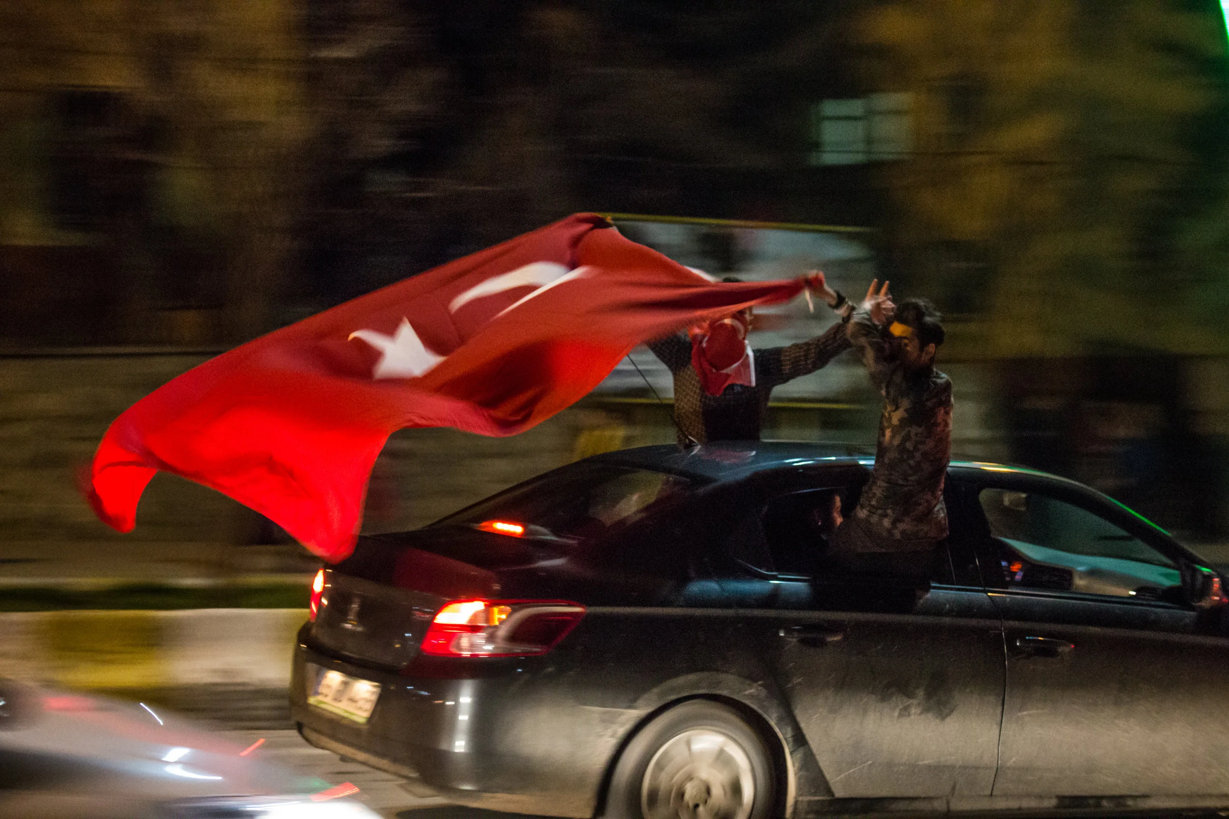 Members of the "Grey Wolves" - a Turkish ultra-nationalist neo-fascist terrorist group which serves as the Nationalist Movement Party's (MHP) paramilitary or militant wing - celebrating the decision of the April 2017 referendum held under a state of emergency declared following a "failed military coup", most likely staged by the government in order to purge political dissidents in July 2016. The referendum - in which the Supreme Electoral Council (YSK) made the unprecedented move to allow non-stamped ballots (1.5 million) to be accepted as valid - was condemned by the OSCE and PACE as illegal and sparked large-scale pro-democracy protests, but will nonetheless allow Recep Tayyip Erdogan to stay in power until 2029. This photograph, taken the night of the referendum win in Mush, shows one of several cars full of Grey Wolves members flashing their wolf-head hand signs at a group of Armenians visiting their ancestral homeland. The group had formed death squads and were responsible for several massacres, as well as the attempted assassination of Pope John Paul II. During the 1970's they killed 700 activists, intellectuals, labor organizers, journalists, and officials - and nearly 6,000 people in total They are openly hostile to all Armenians, Kurds, and Greeks in Turkey, Christians overall, and Jews; and are also credited with the distribution of Adolf Hitler's Mein Kampf in Turkish. Their motto is, "Your doctor will be a Turk and your medicine will be Islam". The context for the "referendum" was made possible by the 2016 coup attempt, which resulted in over 300 people killed and more than 2,100 injured. Mass arrests followed with at least 40,000 detained, including at least 10,000 soldiers and, for reasons that remain unclear, 2,745 judges. 15,000 education staff were also suspended and the licenses of 21,000 teachers working at private institutions were revoked - with over 100,000 arrested or fired from their jobs. The government also released roughly 38,000 prison inmates, to "make more space in the penal system" for detainees who were arrested or detained after being involved in or suspected of association with the coup. Erdogan had said, "This uprising is a gift from God to us".