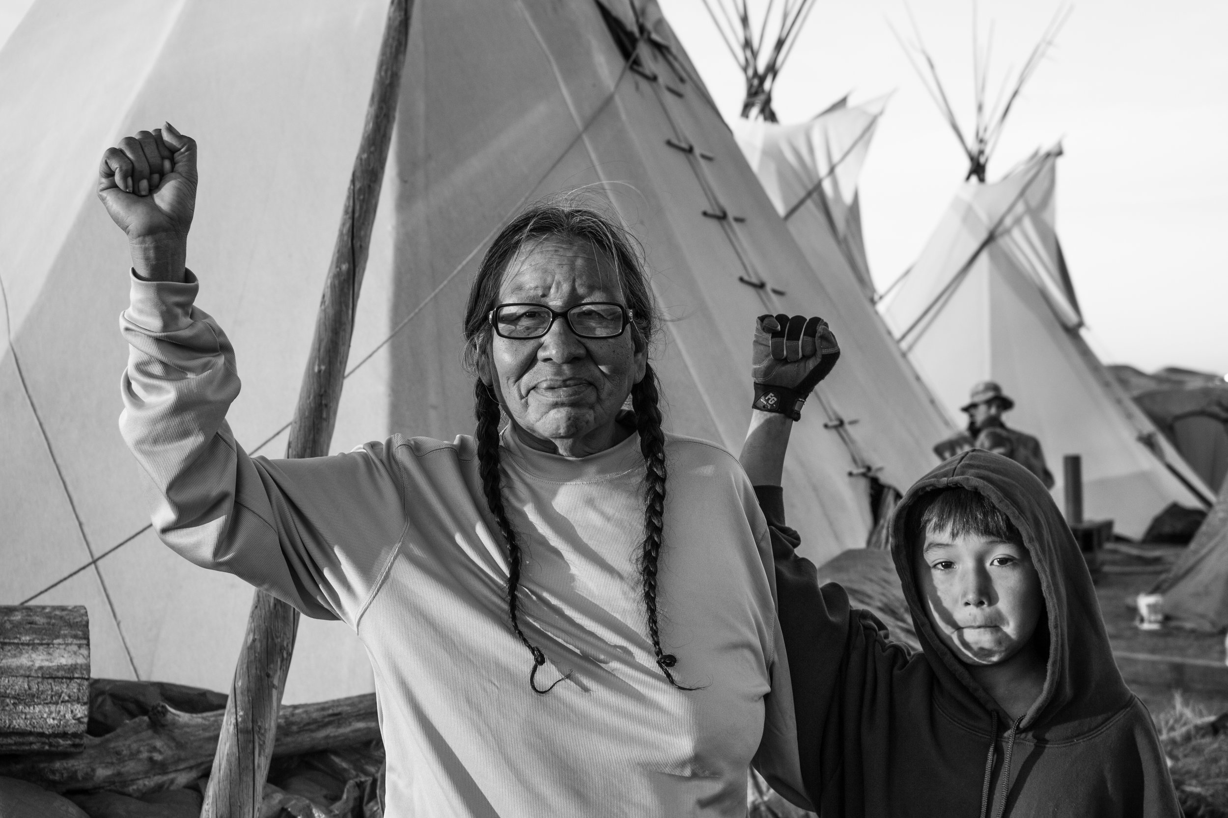 Catka Winyan, known by her friends as Dorothea Sun Bear, stands with her grandson in front of their thípi. Catka lives in what is now Wounded Knee, South Dakota, and is Oglala Lakota Sioux - the people of Chief Crazy Horse. She came to Standing Rock after her grandson showed her a video of an elderly woman being assaulted by a police officer and told me that she's very grateful for social media. She also spoke to me at great length and detail about what brought her to this point in time and space. From the defeat of Custer onward, how they used to be a nomadic people and how they fell on hard times after the buffalo population was decimated. She told me about the Wheeler-Howard Act, or Indian Reorganization Act, in 1934 that was forced on them. The Wounded Knee Massacre and the "allotments" of land “given” by the government. The eminent domain seizures thereafter. The establishment of the first international indigenous embassy on the Pine Ridge Reservation. The Red Cloud tribal building takeover in 2000. How they were formally recognized by the UN in 1977, but still have their rights violated to this day. Born Cha-O-Ha, "In The Wilderness" or "Among the Trees", Crazy Horse died in 1877, after being killed for leaving the reservation without permission. He once said, "My lands are where my dead lie buried." His last were, "My friend, I do not blame you for this. Had I listened to you this trouble would not have happened to me. I was not hostile to the white men... We preferred our own way of living. We were no expense to the government. All we wanted was peace and to be left alone... Our first impulse was to escape with our squaws and papooses, but we were so hemmed in that we had to fight. After that, I went up on the Tongue River with a few of my people and lived in peace. But the government would not let me alone. Finally, I came back to the Red Cloud Agency. Yet, I was not allowed to remain quiet. I was tired of fighting. I went to the Spotted Tail Agency and asked that chief and his agent to let me live there in peace. I came here with the agent Lee to talk with the Big White Chief but was not given a chance. They tried to confine me. I tried to escape, and a soldier ran his bayonet into me. I have spoken." Even in death Crazy Horse refused to lie on a cot and insisted on being placed on the ground. Armed soldiers stood by until he died and when he breathed his last breath, Touch the Clouds - his seven-foot-tall Miniconjou friend - pointed to the chief's body and declared, "This is the Lodge of Crazy Horse".