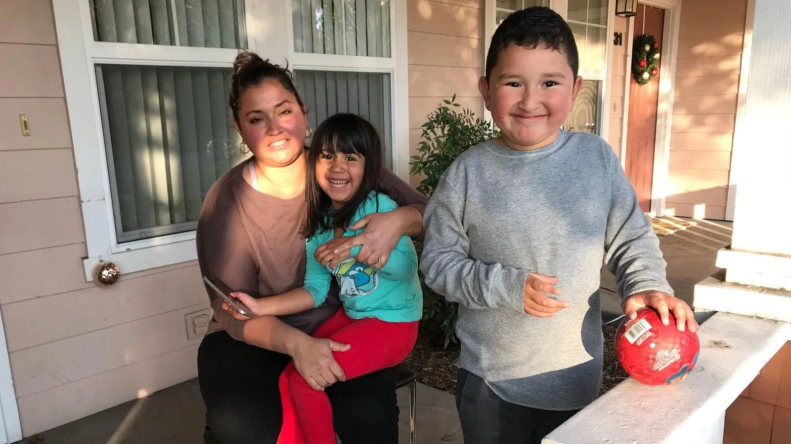 After spending two months sleeping in a friend's living room, the Alvarez family of Calistoga, who lost their home and their jobs, found a rent-subsidized condo in Cotati. Here, Claudia, 34, sits with children Sofia, 4, and Steven, 7, on their new front porch. (Robin Abcarian / Los Angeles Times)