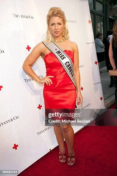 Miss Canada, Shannon Smadella wearing a red dress and sash at an event with a Tiffany & Co. backdrop. Wearing $250,000 worth of Tiffany diamonds. Tiffany Women Leaders.