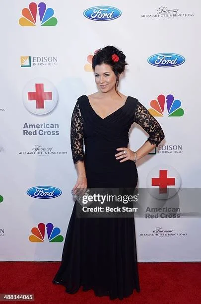 Shannon Smadella in a black lace dress posing on a red carpet with a backdrop featuring logos of NBC, Ford, American Red Cross, Edison International, and other sponsors.