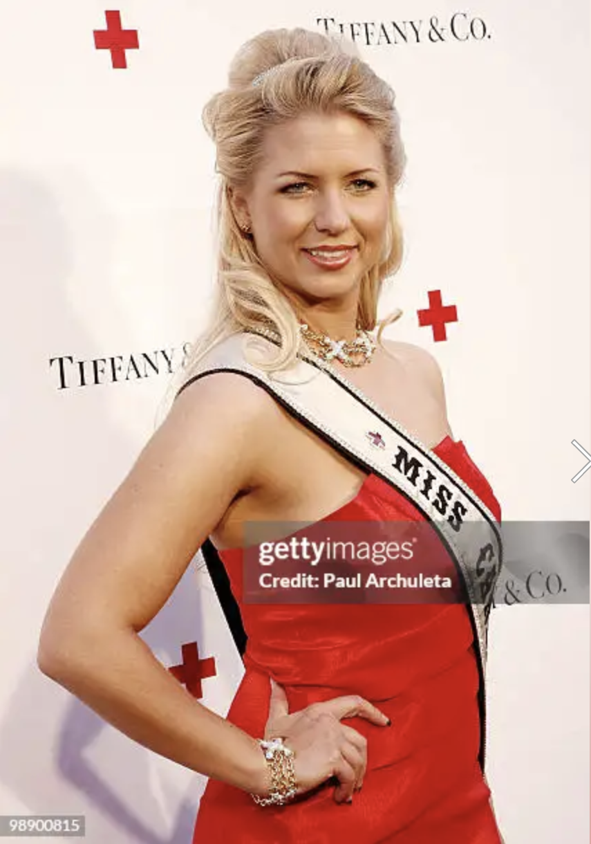 Miss Canada woman wearing a red dress, sash, and jewelry, standing in front of a backdrop with red crosses and 'Tiffany & Co.' branding.