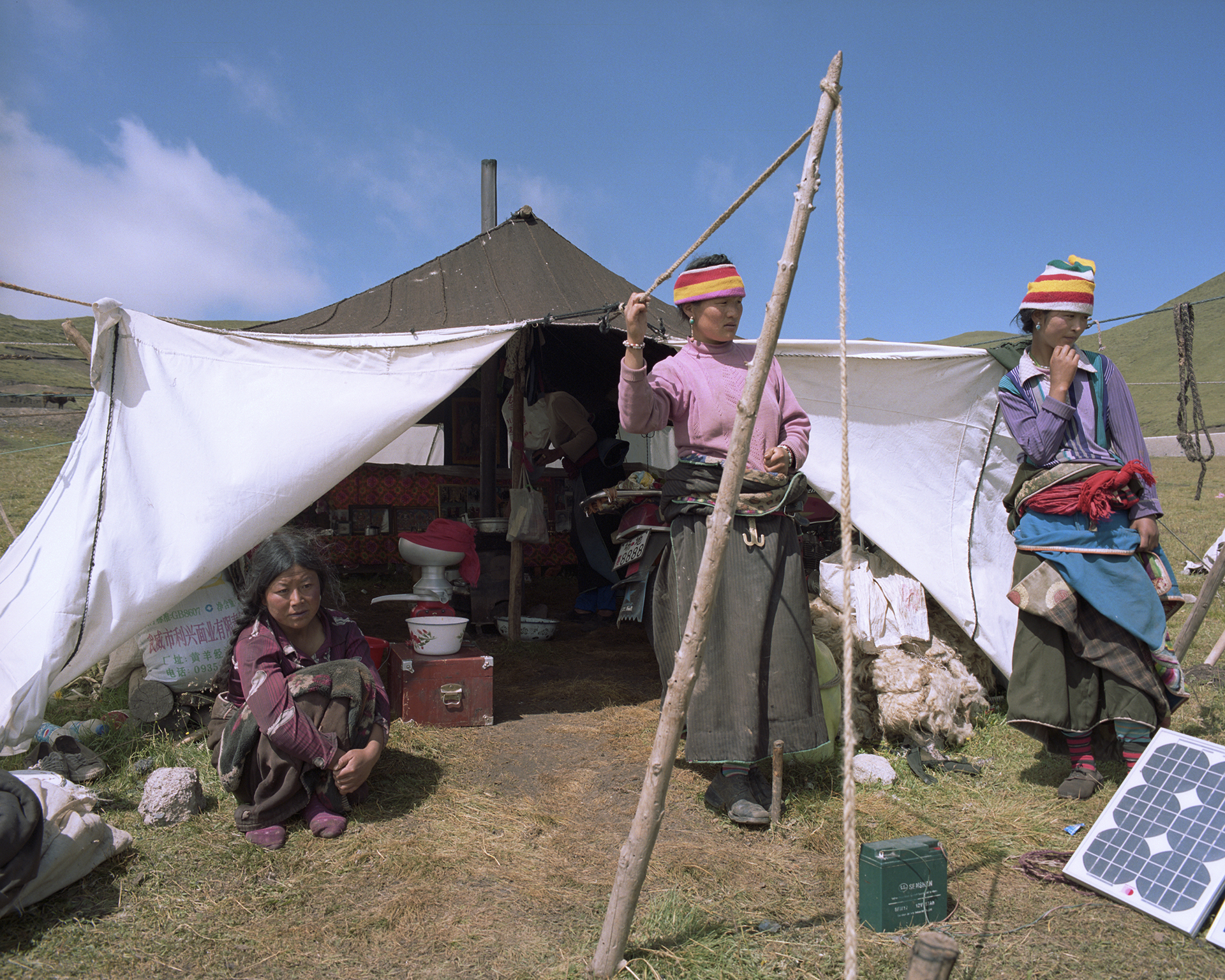 2007-Qinghai -Nomad women at their tent. Many of the men will be deeper into the mountains with most of the yak. Solar power provides electricity for the butter separator and for the mobile phones to keep in contact with each other.