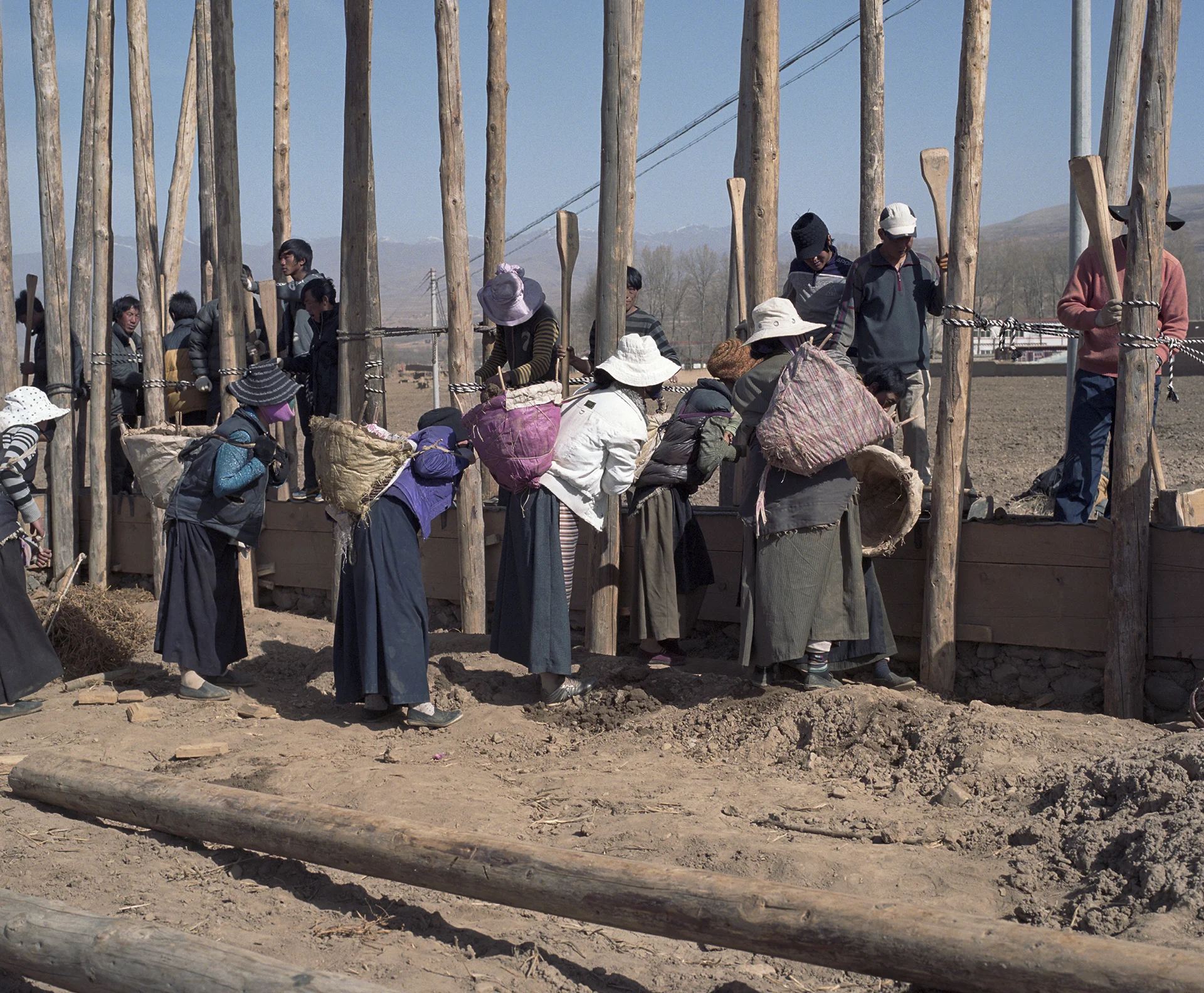 2010, Xianceng - a total village building a mud house together. The women bring the mud. The men stamps that into a wall.