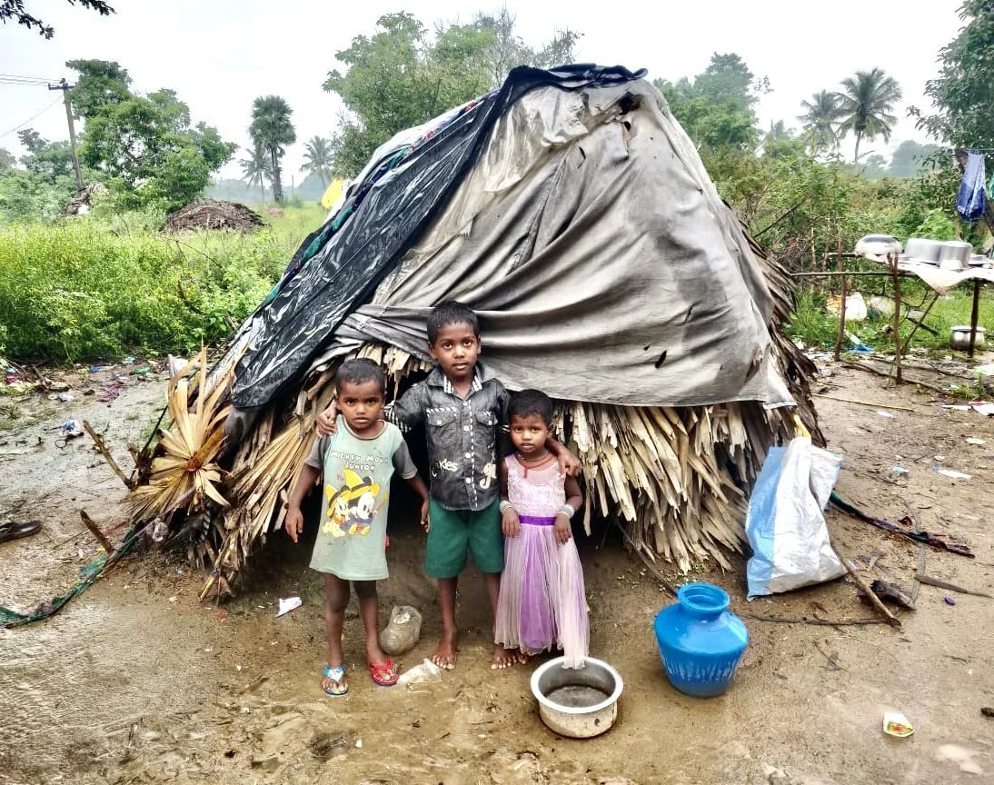 Disadvantaged indian children standing in front of hut after flooding.jpeg