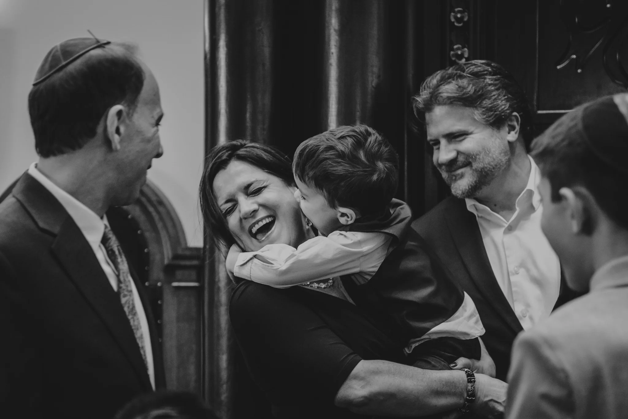 Noah's younger brother tries to give his Mom a kiss on the cheek while posing on the bema for bar mitzvah pictures at Temple Beth Or.