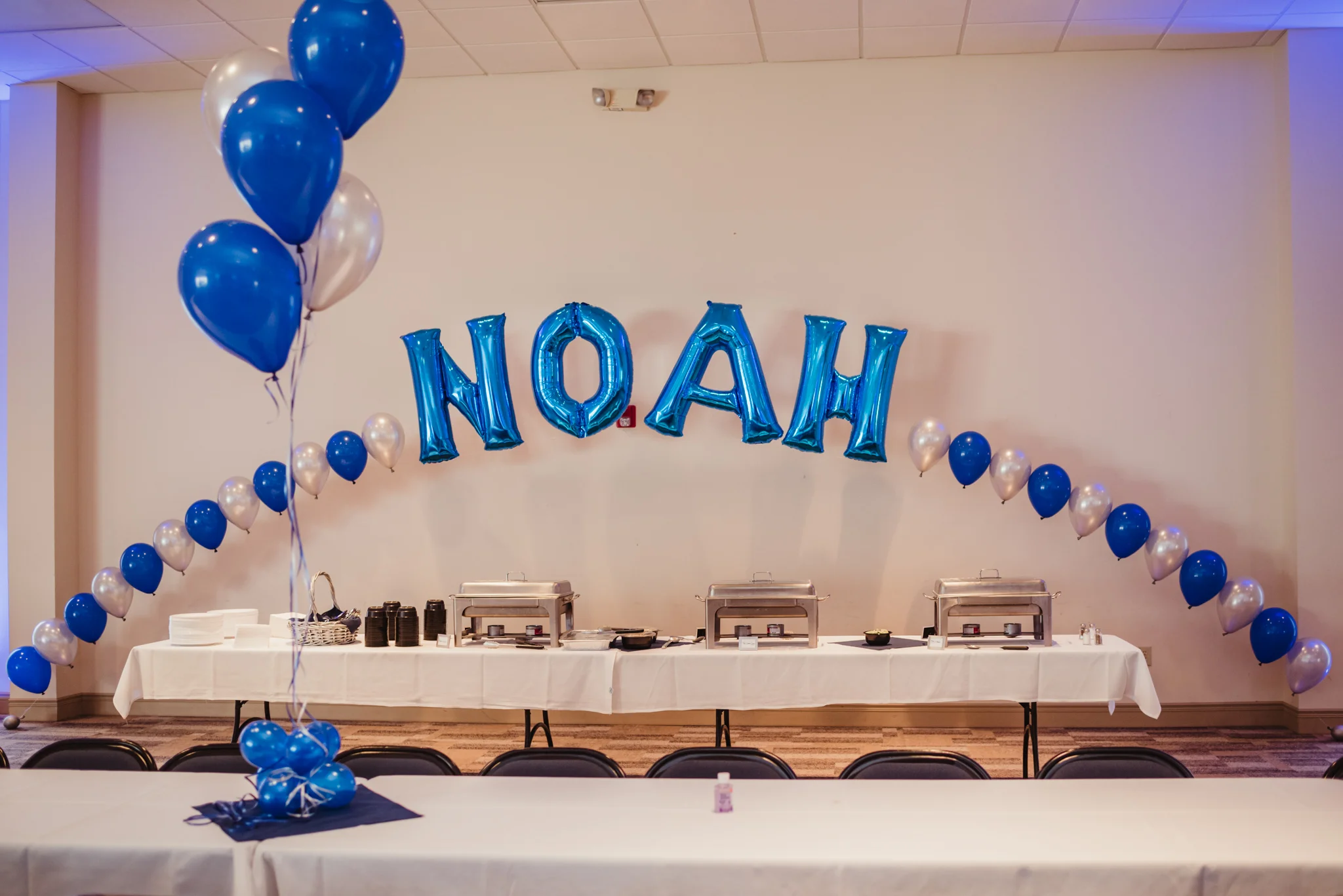 Blue and silver balloons that spell out Noah's name adorn the back of the celebration space at Temple Beth Or.