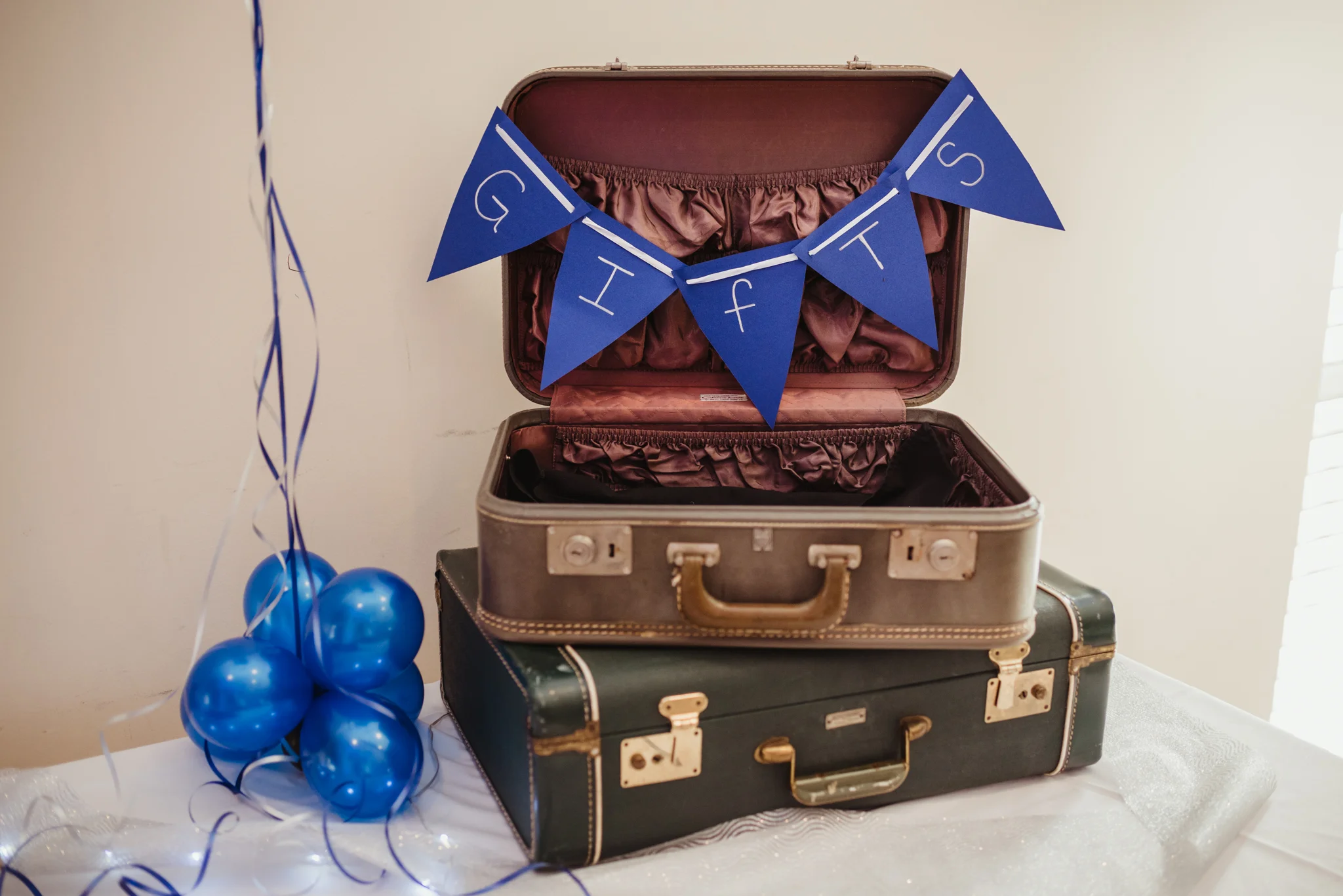 Balloons and suitcases, adorned with a blue banner, are a perfect place for guests to place gifts and cards for the bar mitzvah boy.