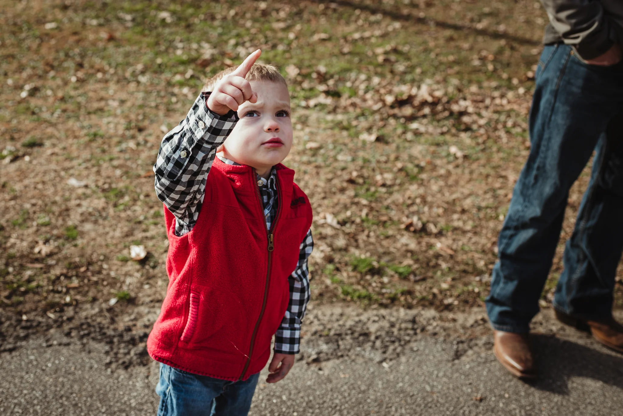 The three year old boy points to the sky during his family photo session in Raleigh, North Carolina.