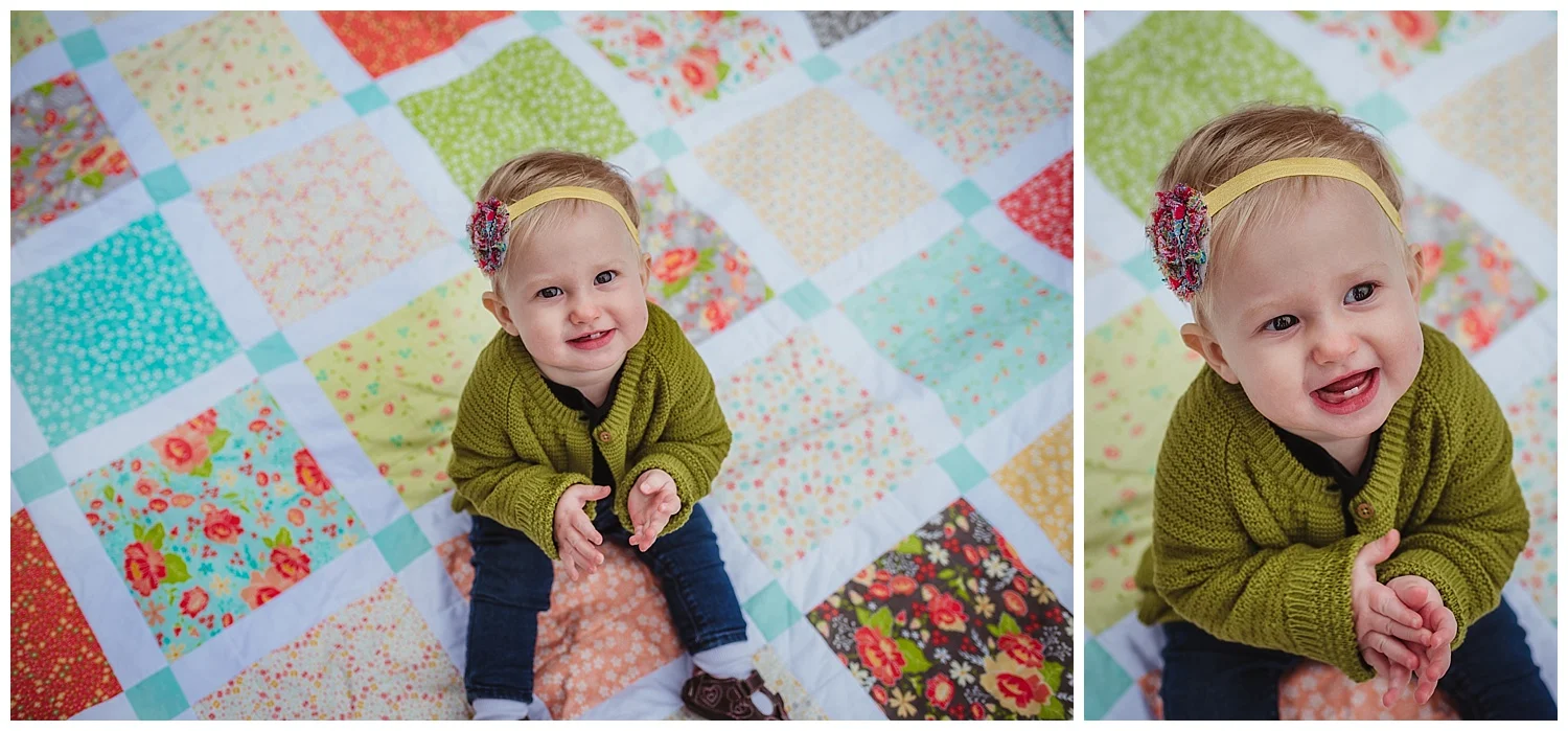 The little girl claps on the handmade quilt during her family photo session in Wake Forest, North Carolina with Rose Trail Images.
