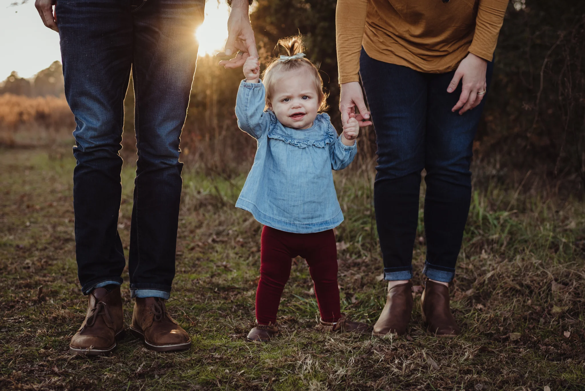This young family of three stands with their young daughter at sunset during their family photo session with Rose Trail Images at Horseshoe Nature Park in Wake Forest, NC.