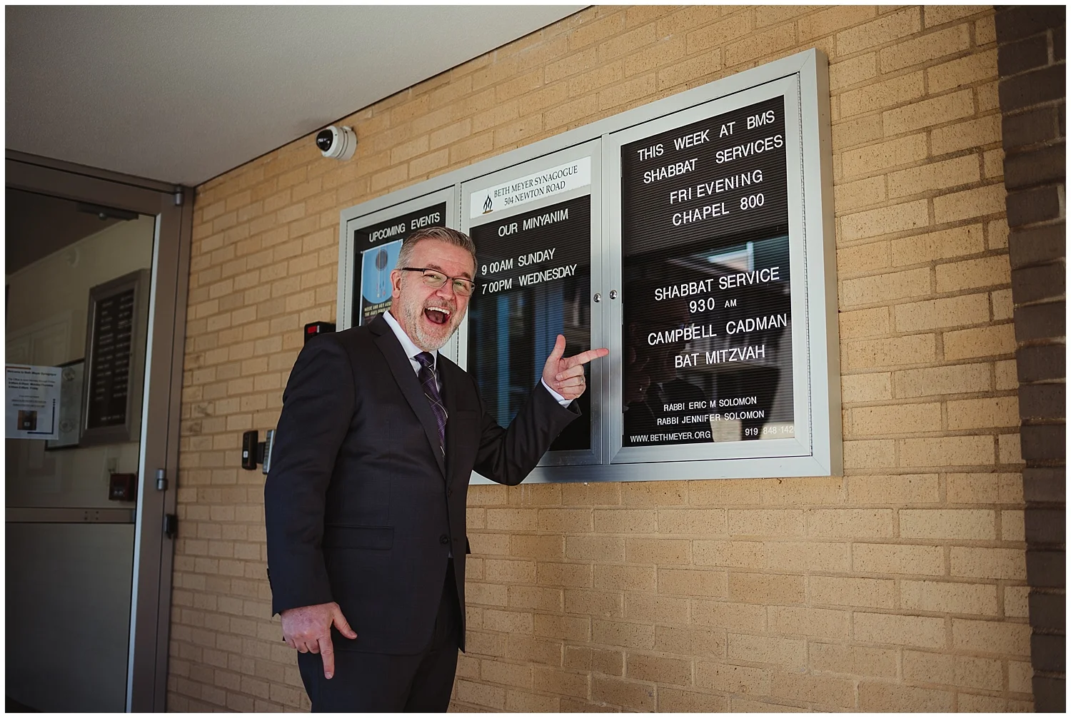 The father of the mitzvah girl poses withe sign out front at Beth Meyer Synagogue in Raleigh, NC.